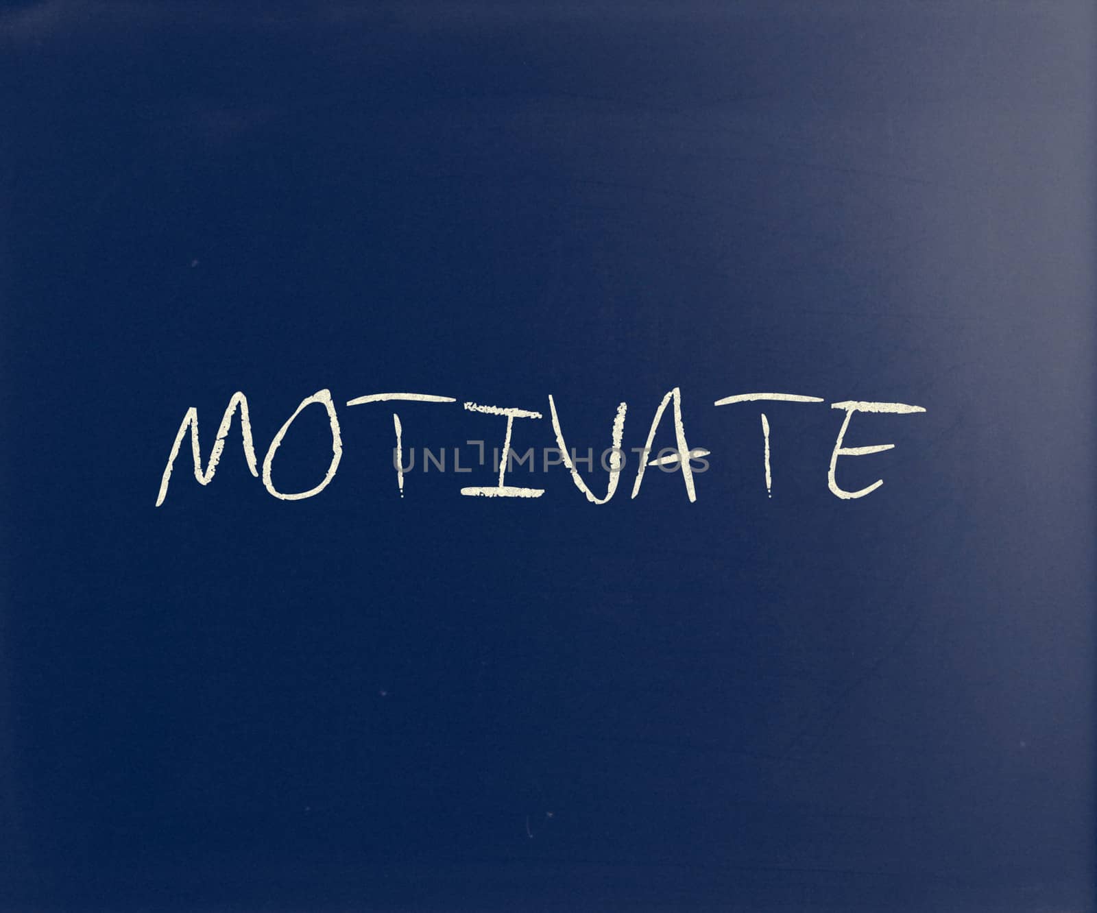 "Motivate" handwritten with white chalk on a blackboard.