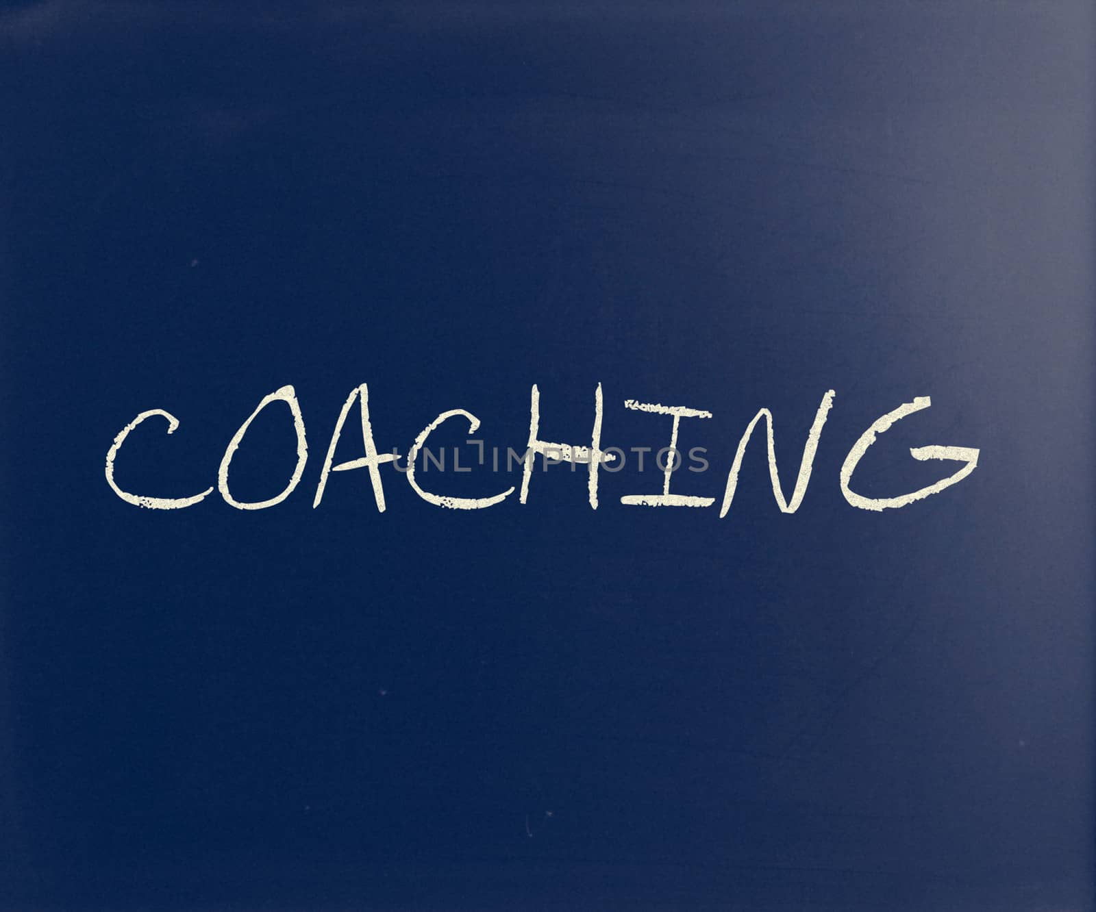 "Coaching" handwritten with white chalk on a blackboard.