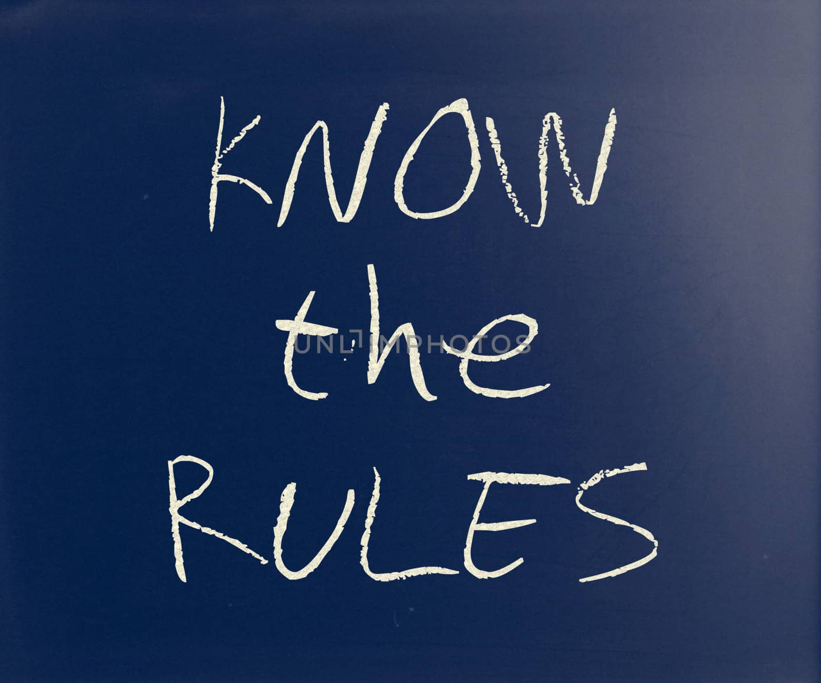 "Know the rules" handwritten with white chalk on a blackboard.