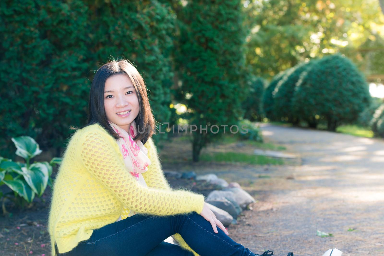 Young woman sitting next to a road looking happy