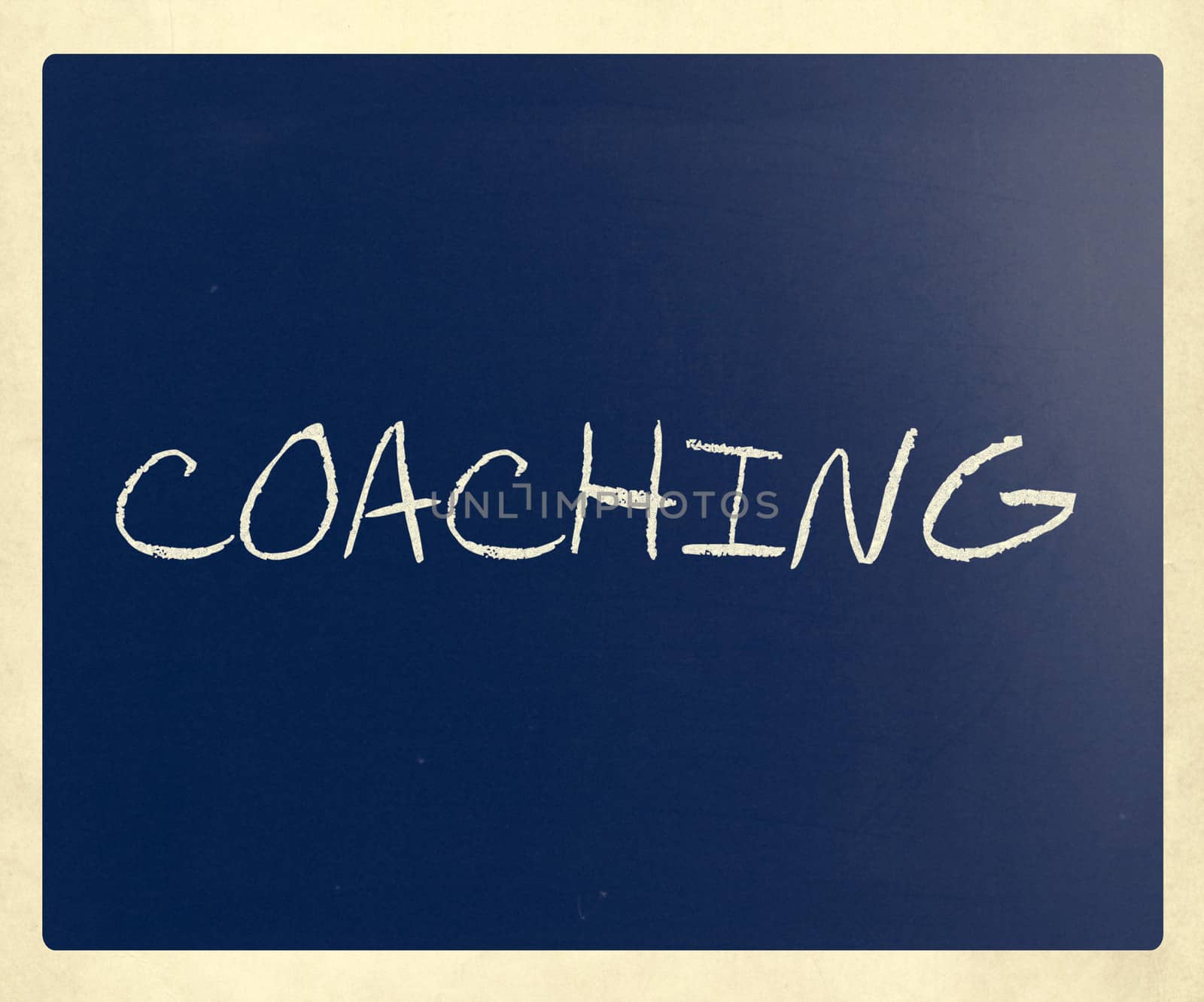 "Coaching" handwritten with white chalk on a blackboard.