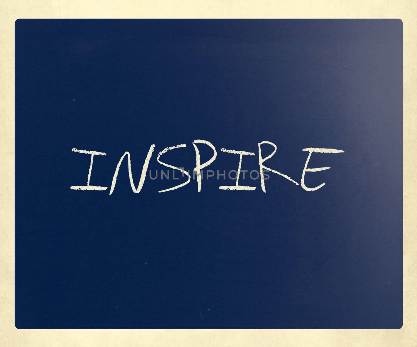 "Inspire" handwritten with white chalk on a blackboard.