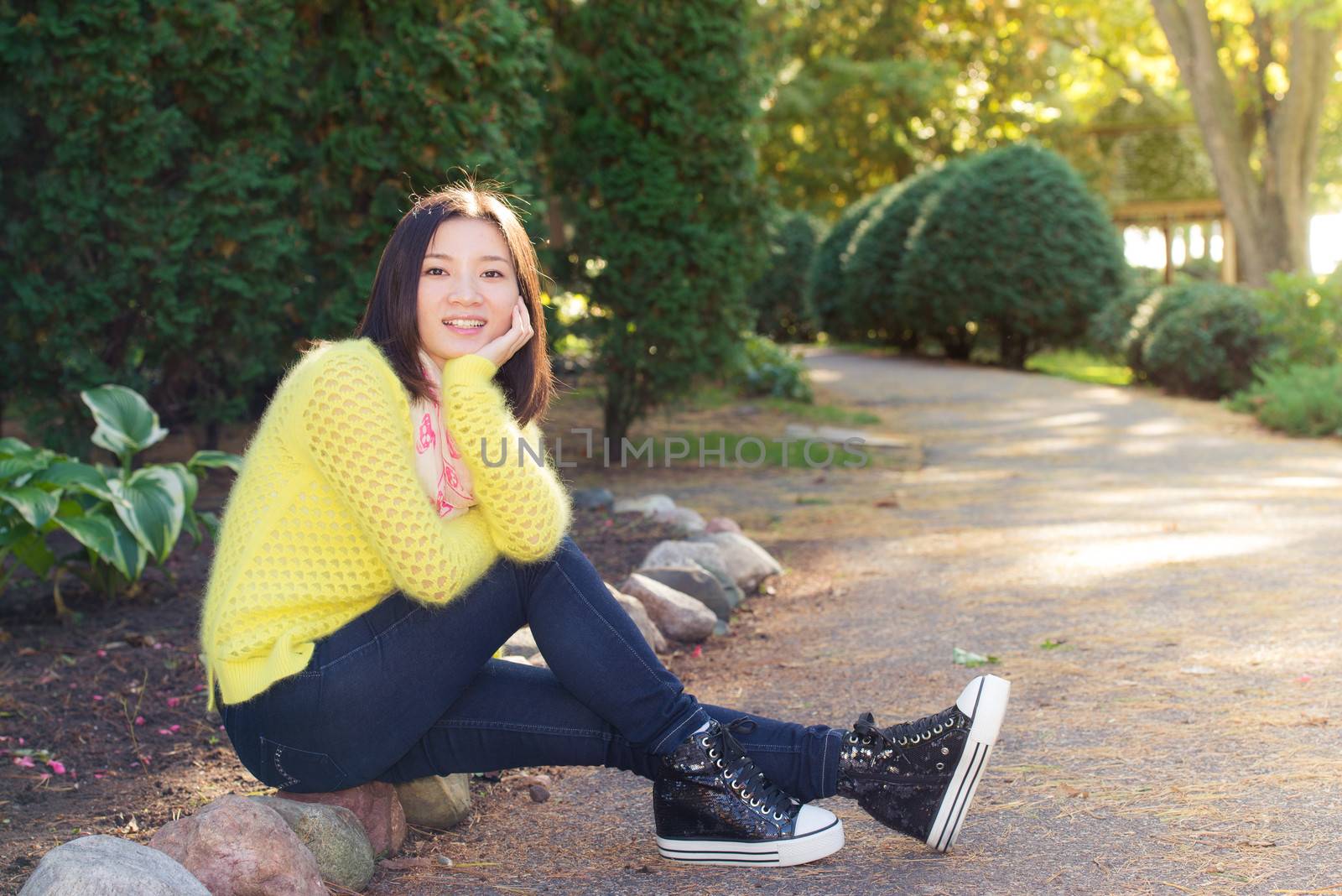 Young woman sitting next to a road looking happy