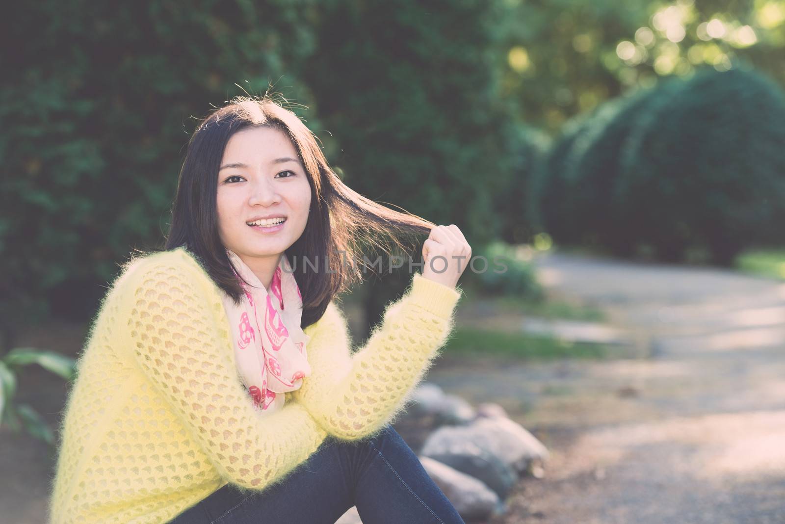 Young woman sitting next to a road playing with her hair