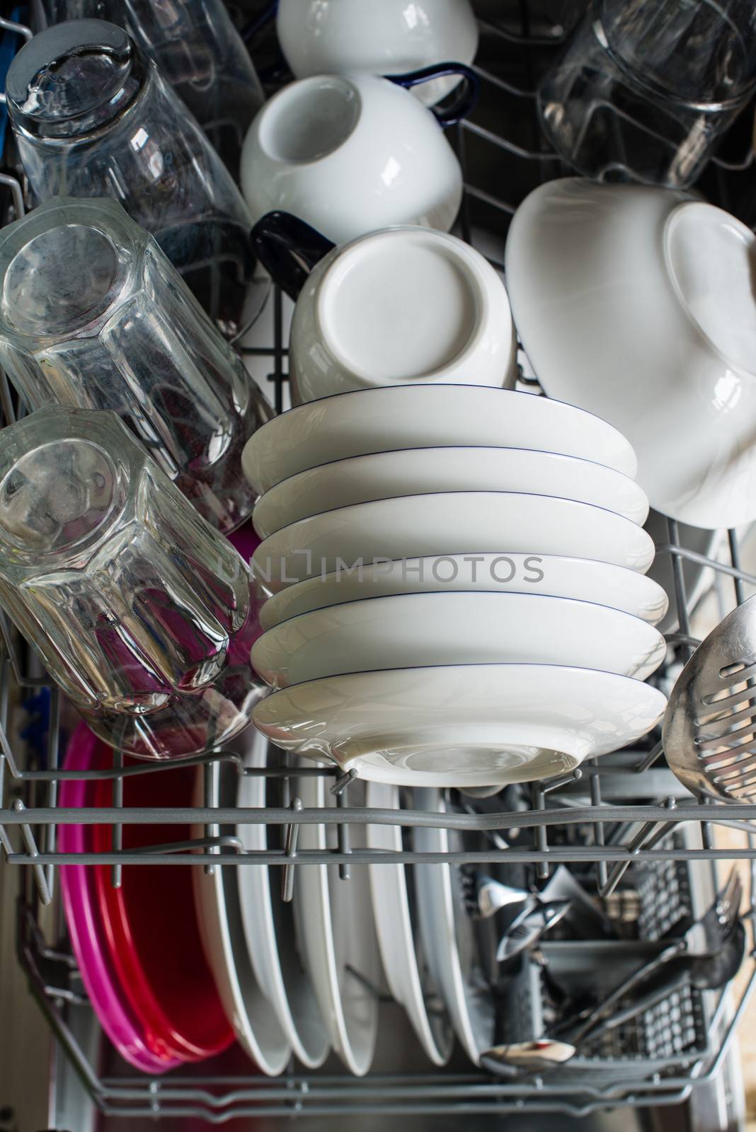 Dishwasher after cleaning process with plates, cups, glasses, cutlery and plastic boxes