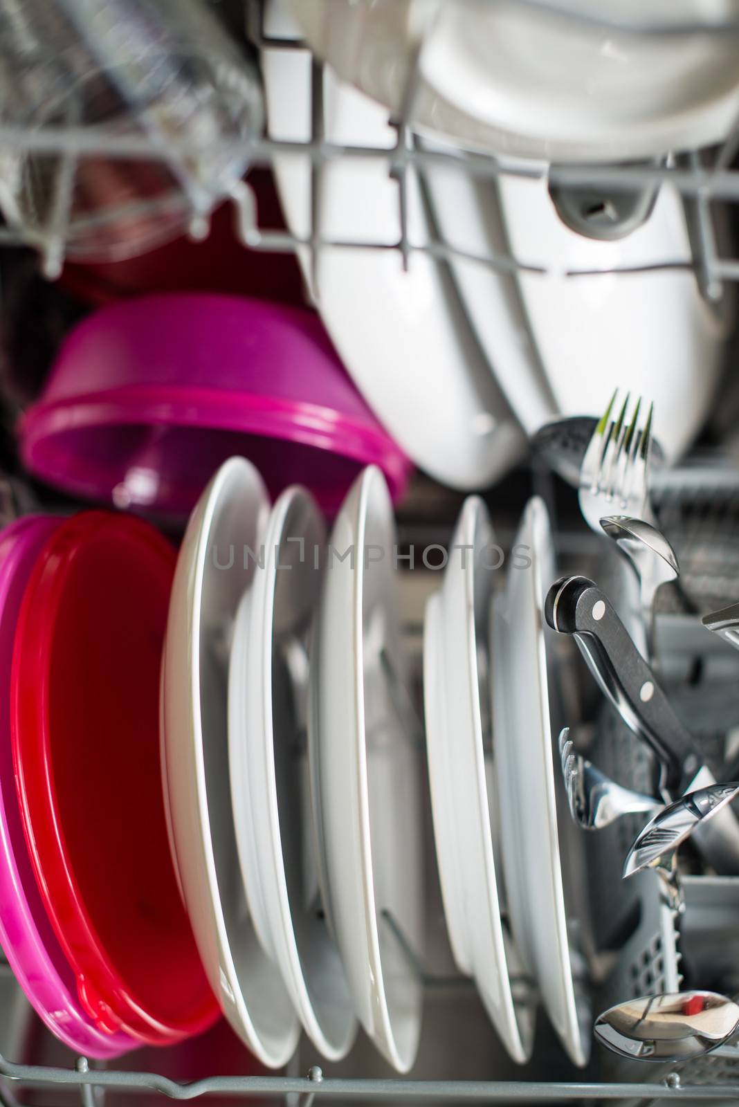 Dishwasher after cleaning process with plates, cups, glasses, cutlery and plastic boxes - shallow depth of field