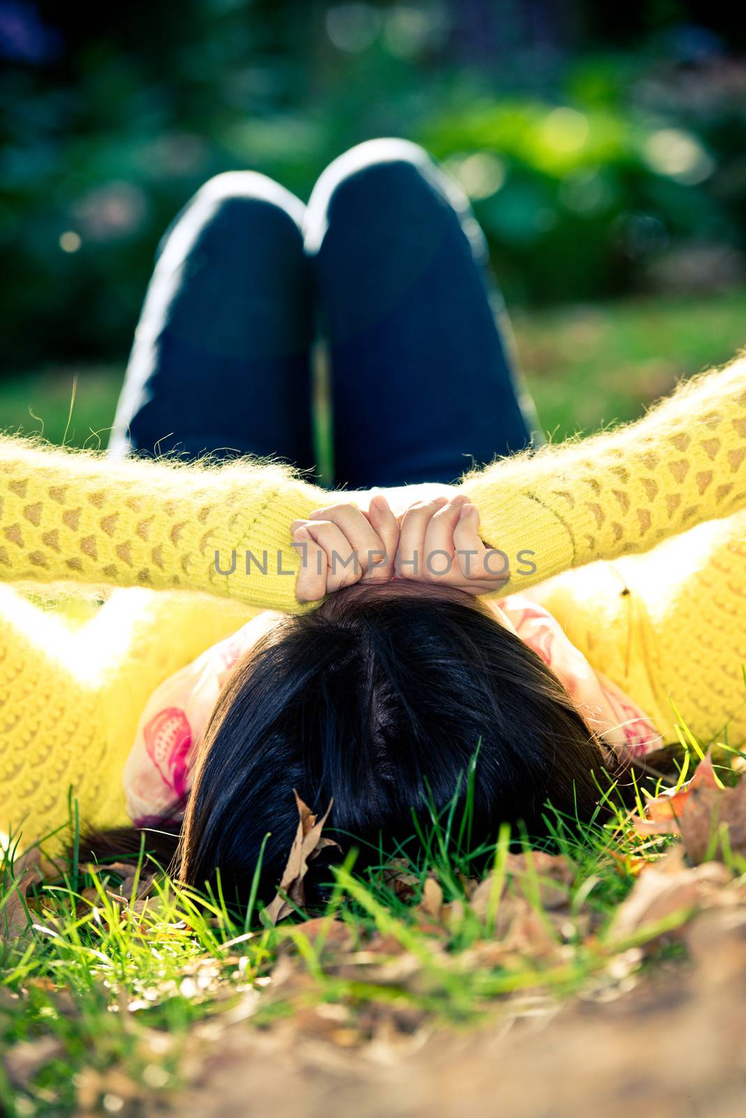 Woman laying in grass by IVYPHOTOS