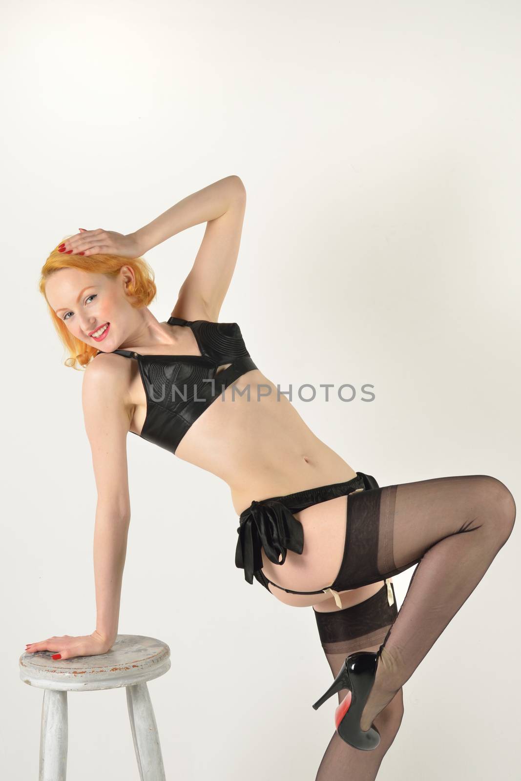 Pretty red head in retro pose leaning on stool