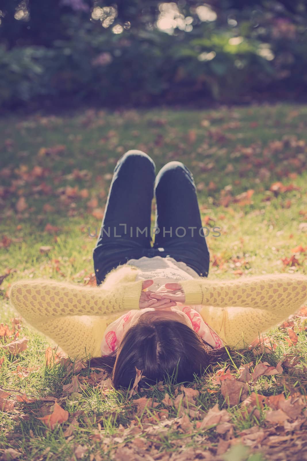Woman laying in grass by IVYPHOTOS