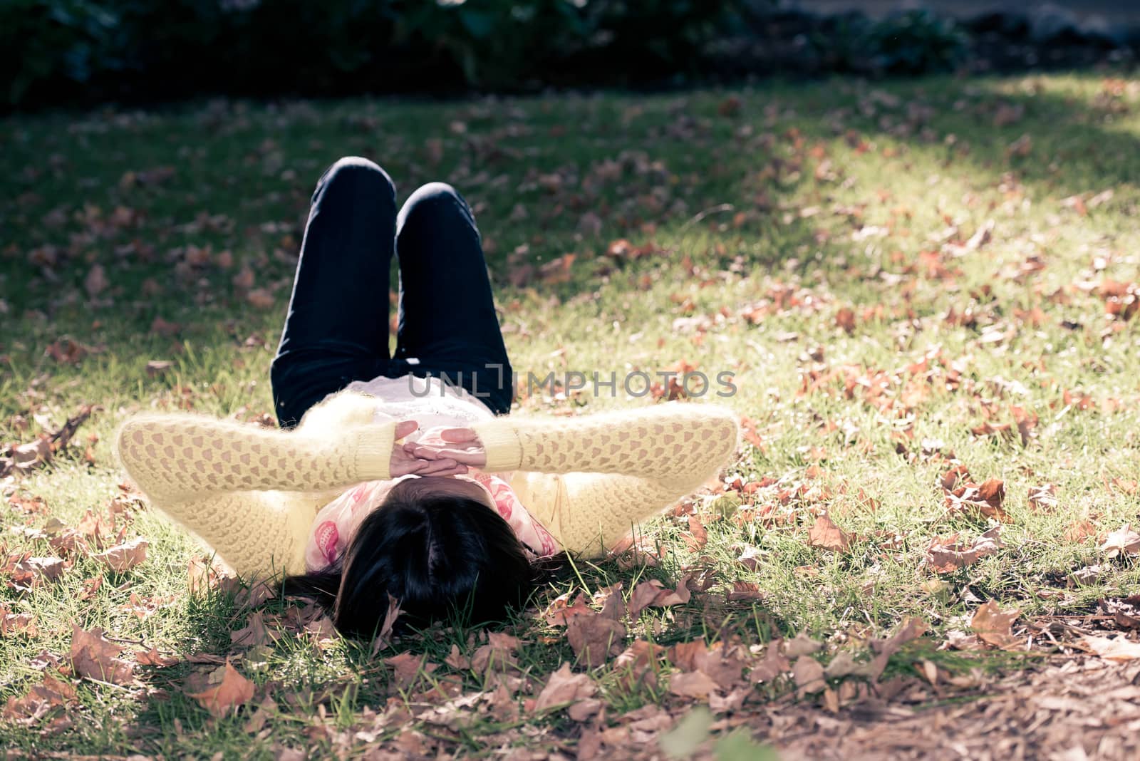 Unique top view of young woman laying in grass with a bunch of fallen leafs