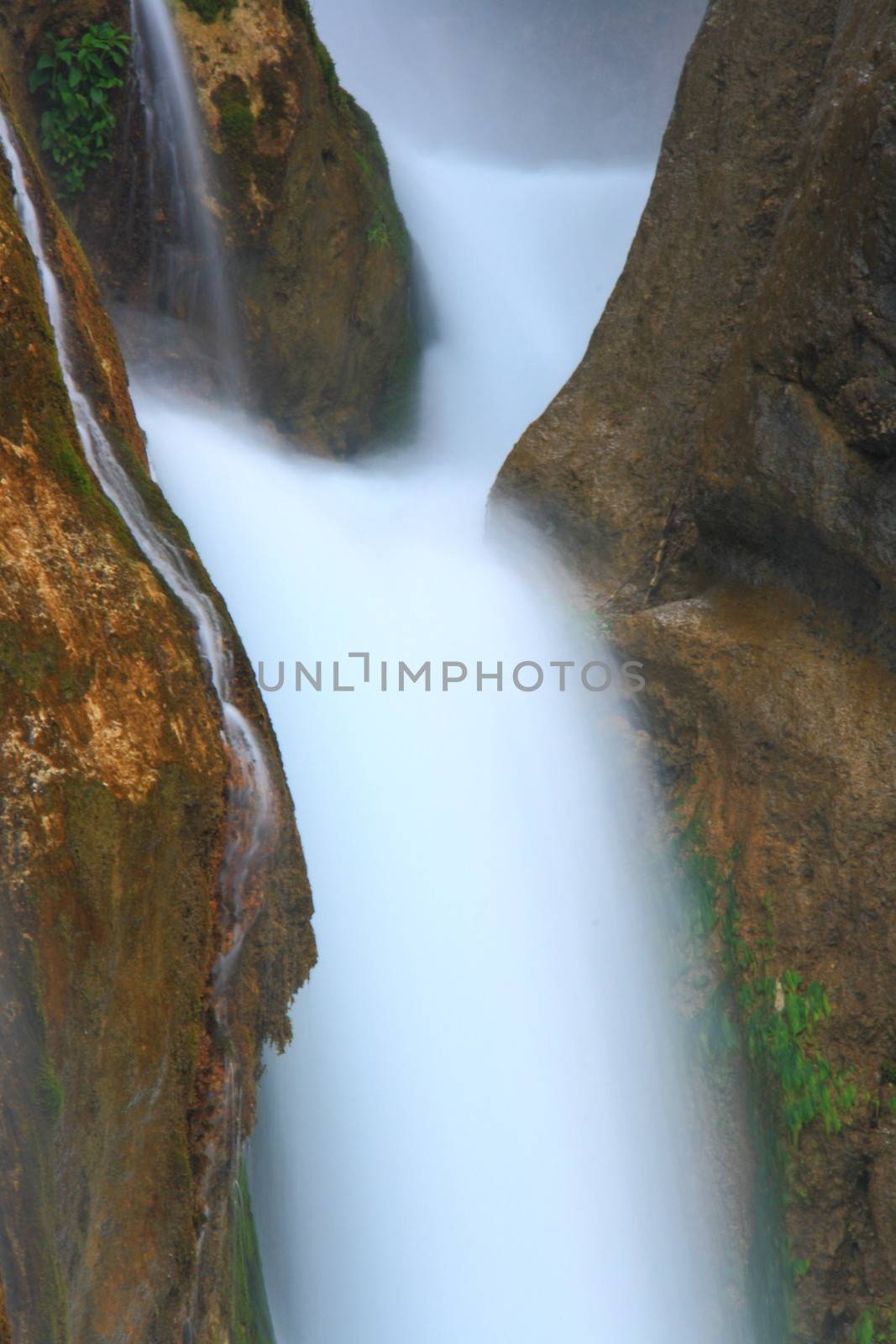 water falling to river between huge rocks 