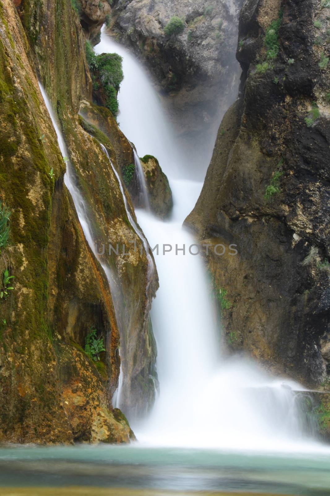 water falling to river between huge rocks 