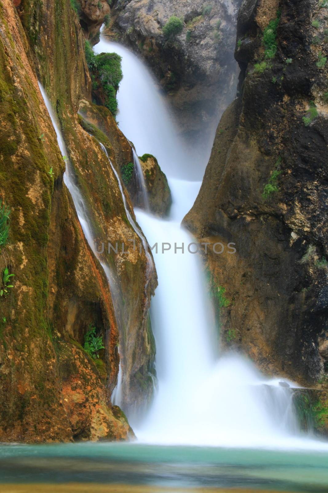 water falling to river between huge rocks 