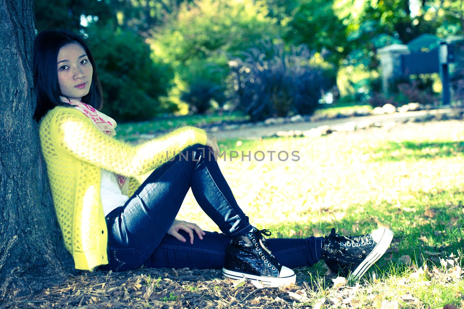 Portrait of lonely young woman sitting against a tree looking upset