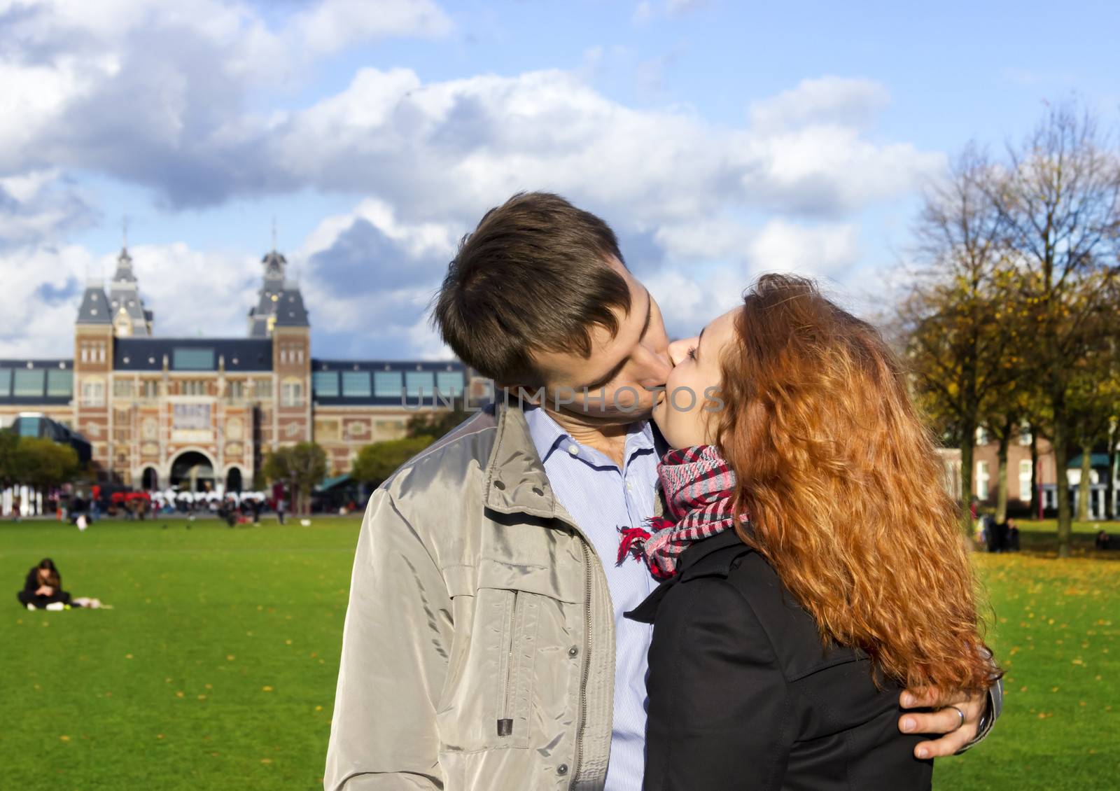 Outdoor happy couple kissing in Museumplein, Amsterdam by Tetyana