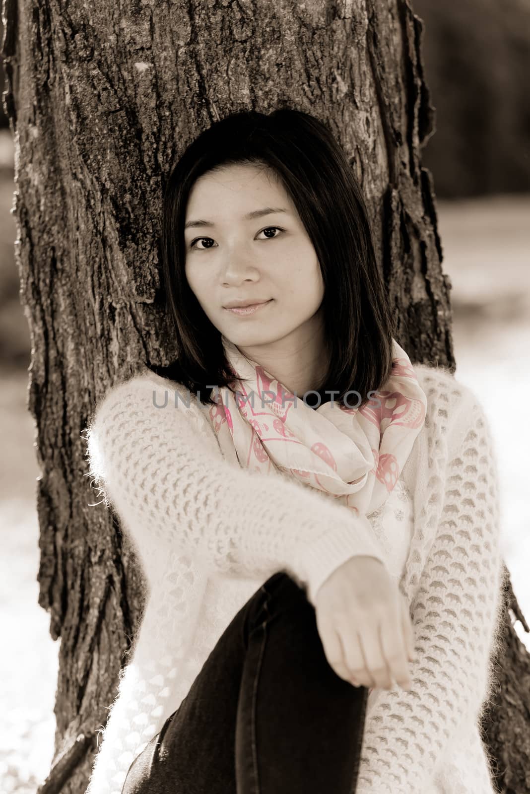 Portrait of happy looking woman sitting against a tree