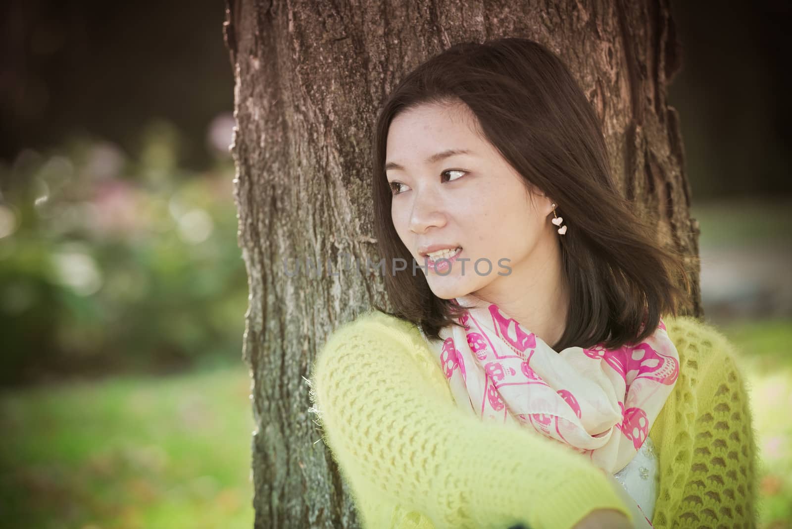 Portrait of happy looking woman sitting against a tree and looking to the side