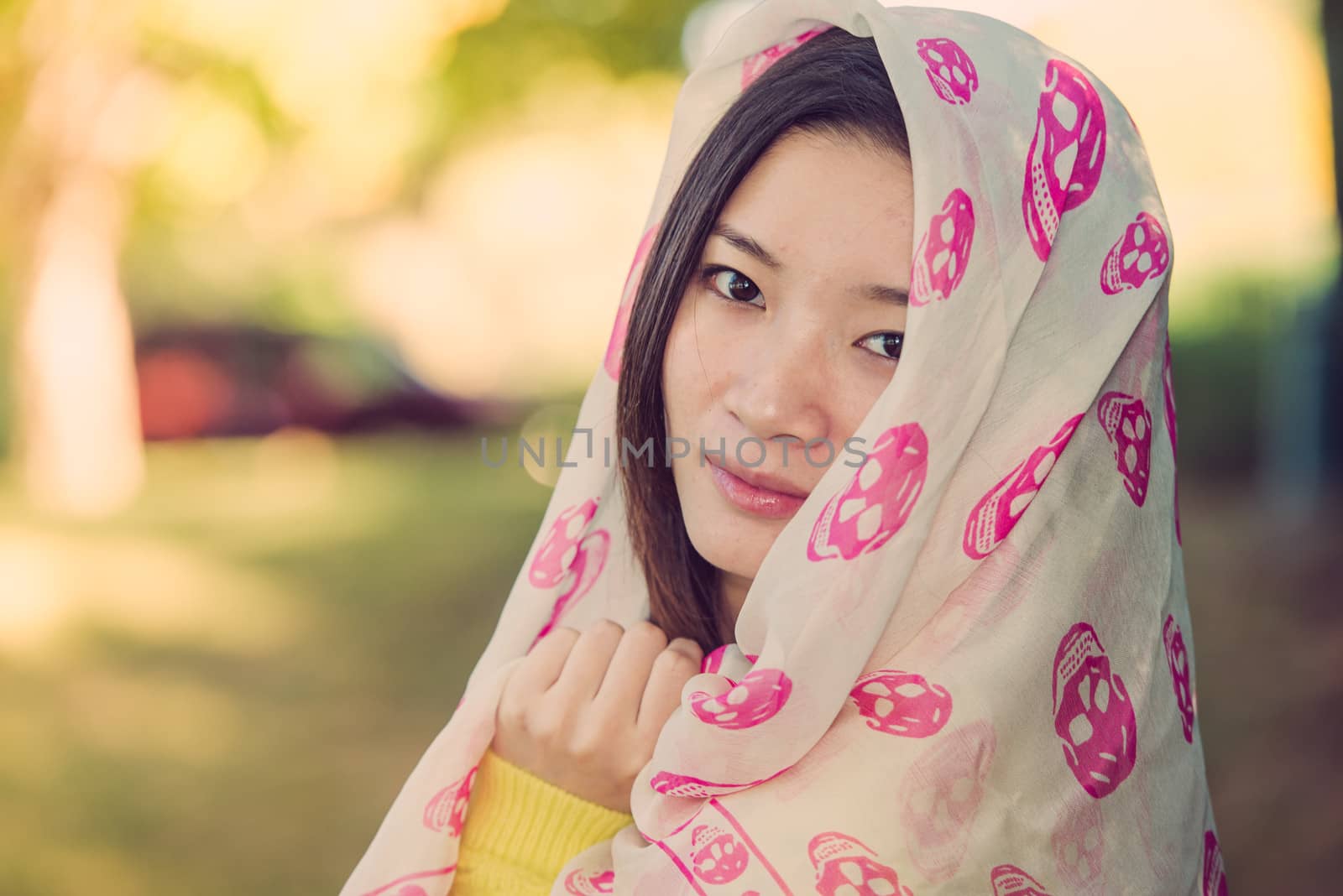 Beautiful young woman with skull covering head and face in sunshine