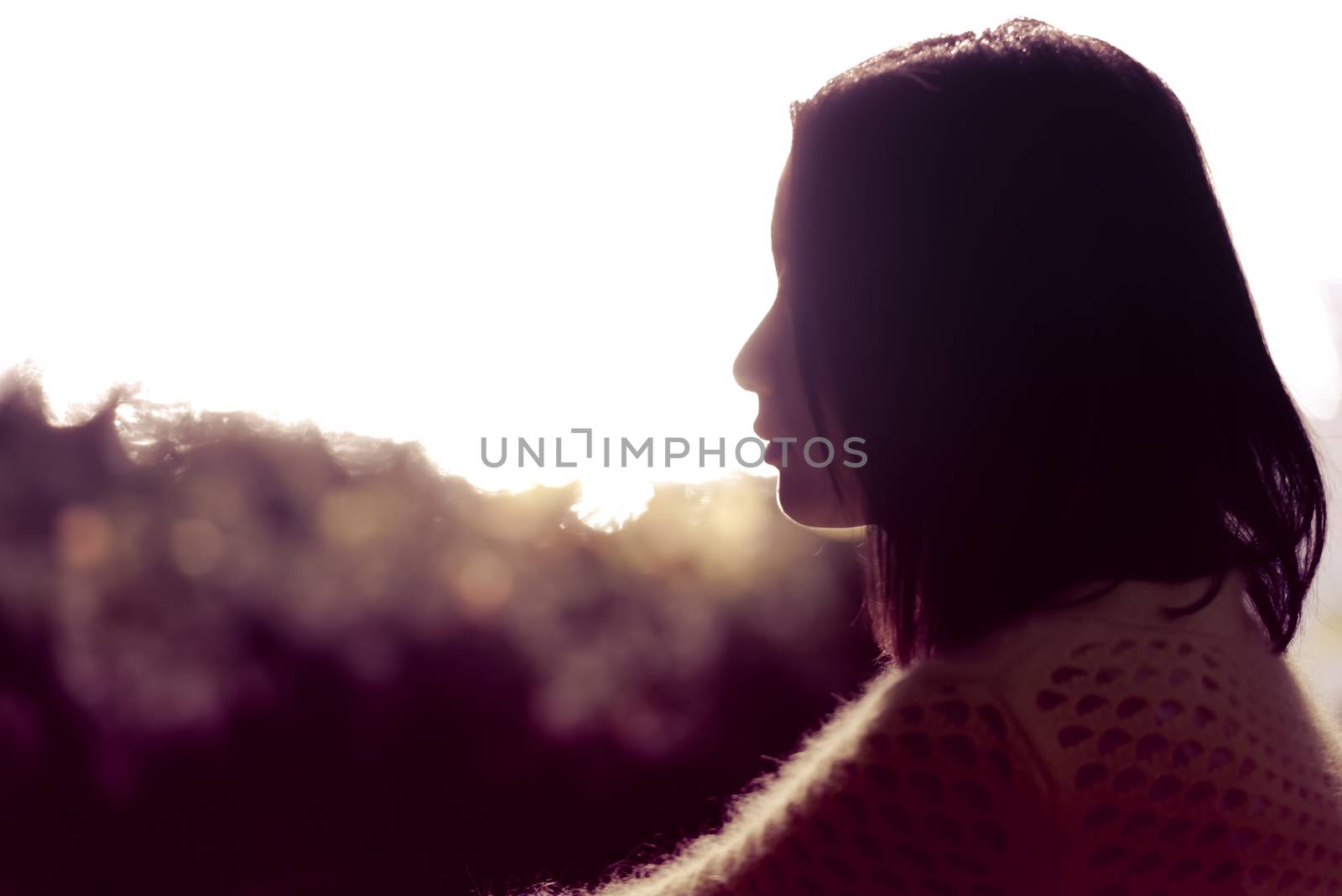 Silhouette portrait of lonely young woman sitting during dusk time