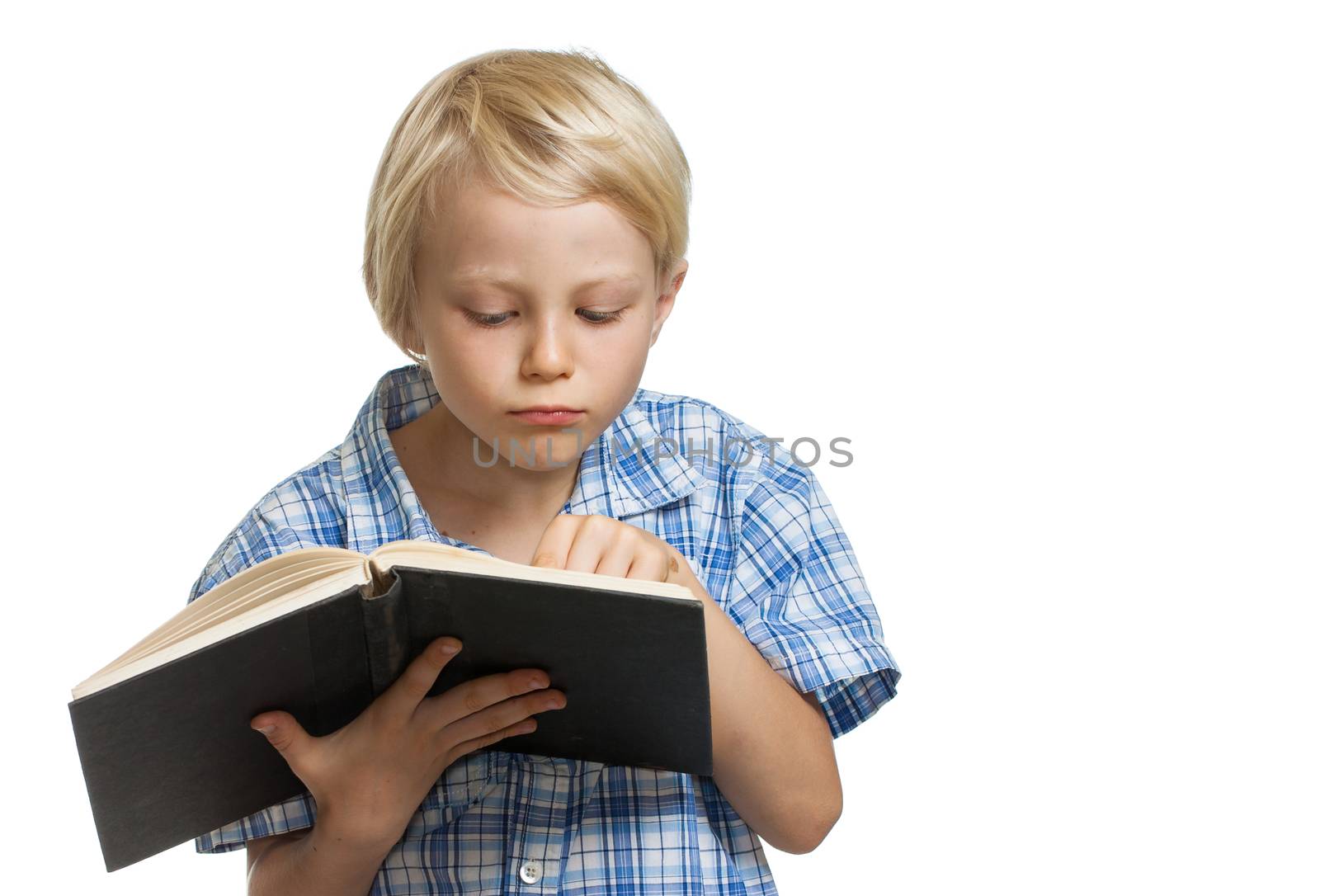 A serious young boy holding and reading a book. Isolated on white.