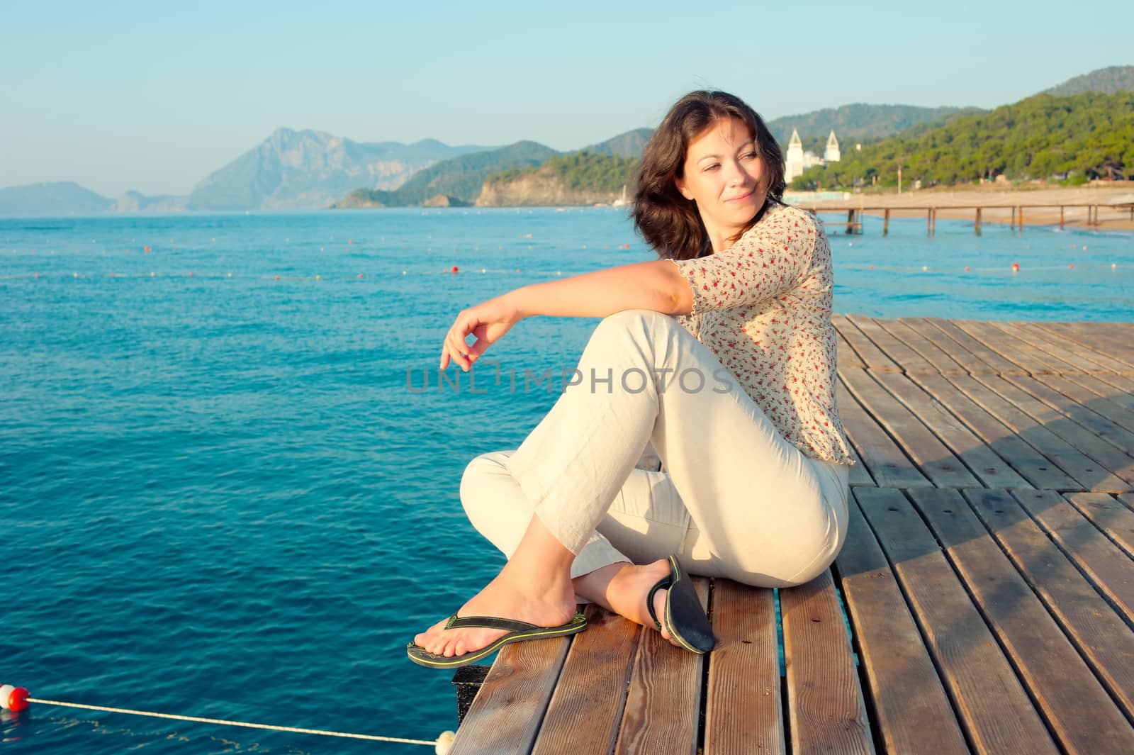 girl sitting on a pier near the sea and looking to the side by kosmsos111