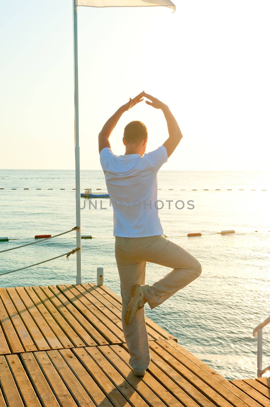 man standing on a pier on one leg and holds the balance