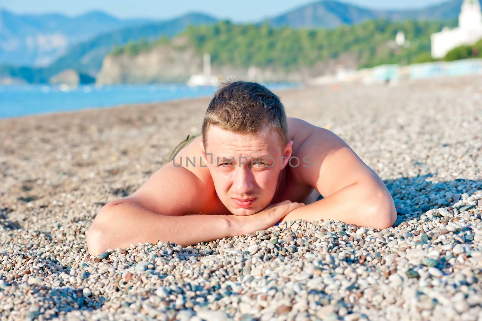 man sunbathes lying on a rocky beach