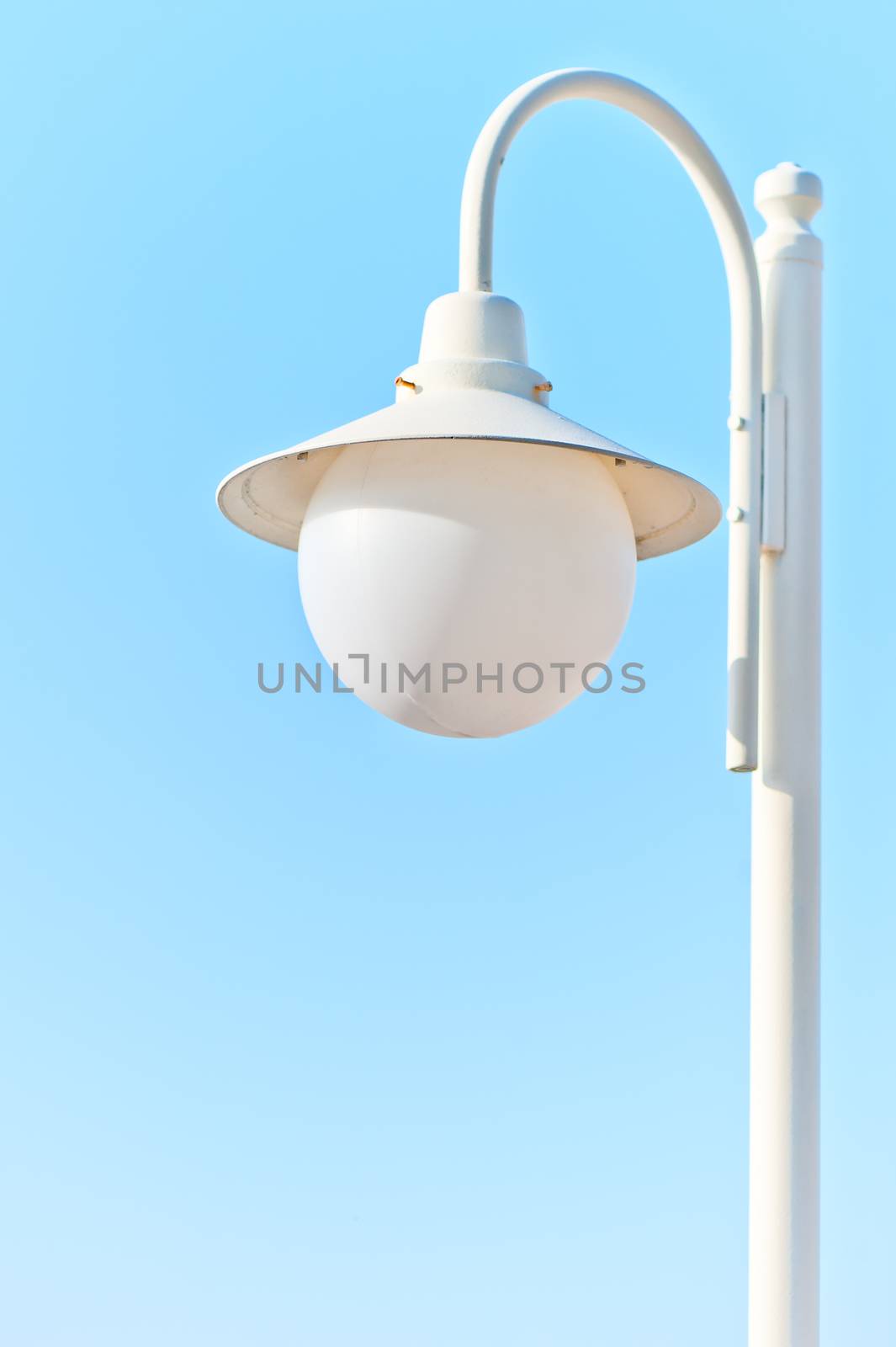 solitary white street light against the blue sky