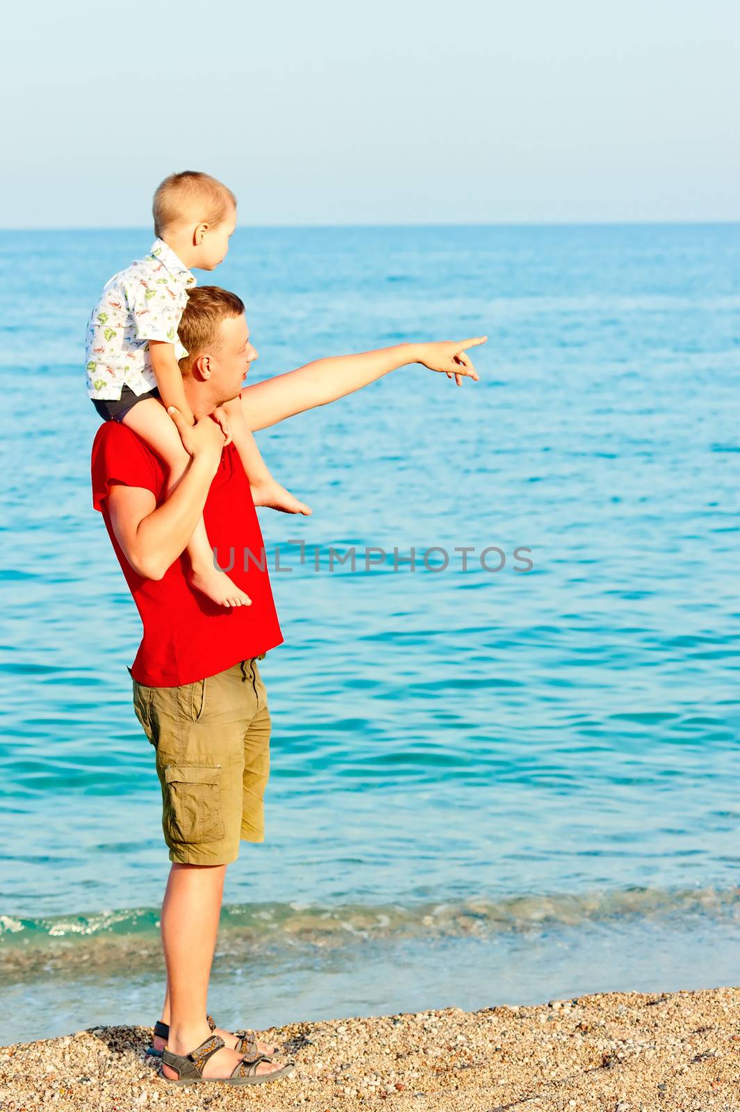 Father showing something to his son in the sea by kosmsos111