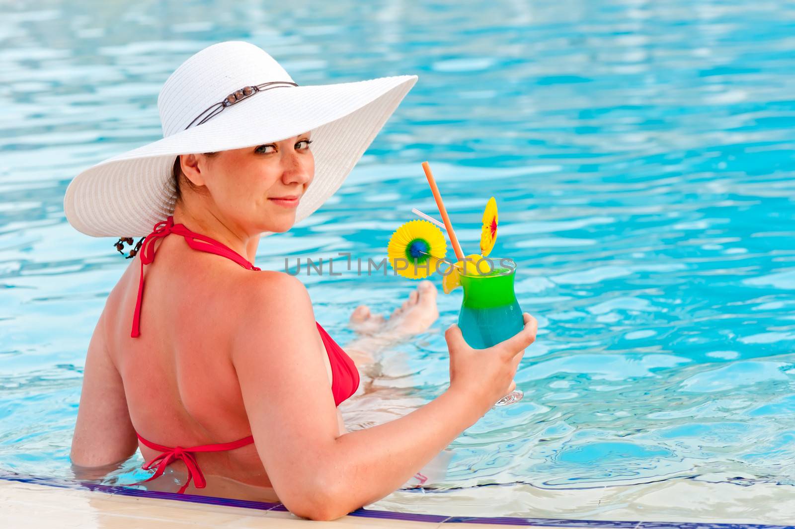 smiling girl with a cocktail at the pool