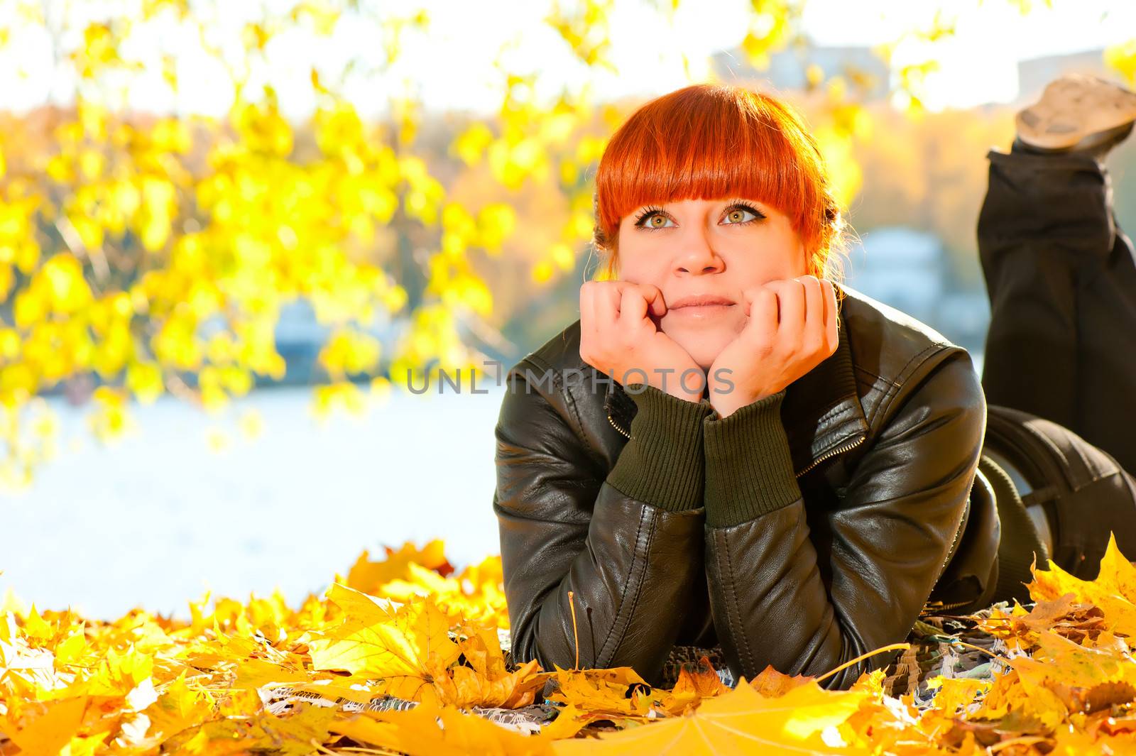 beautiful girl with red hair in leaves in autumn park