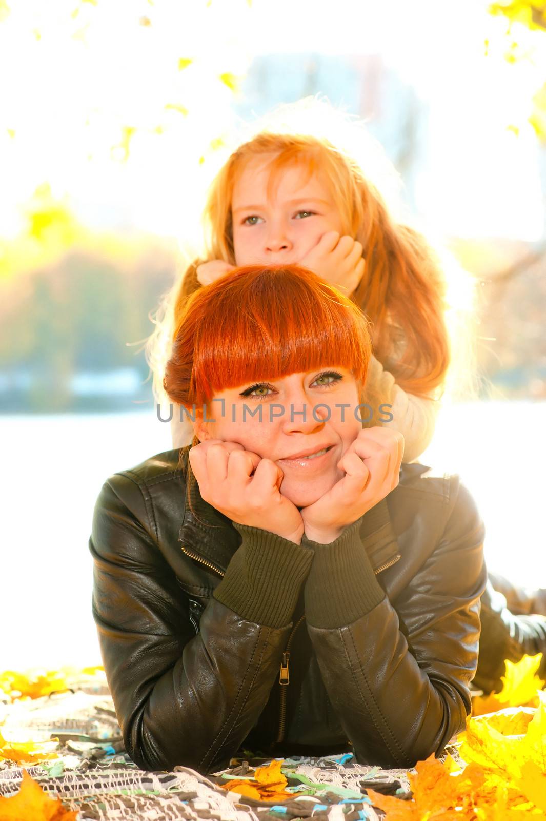 Mother and daughter resting in the autumn park