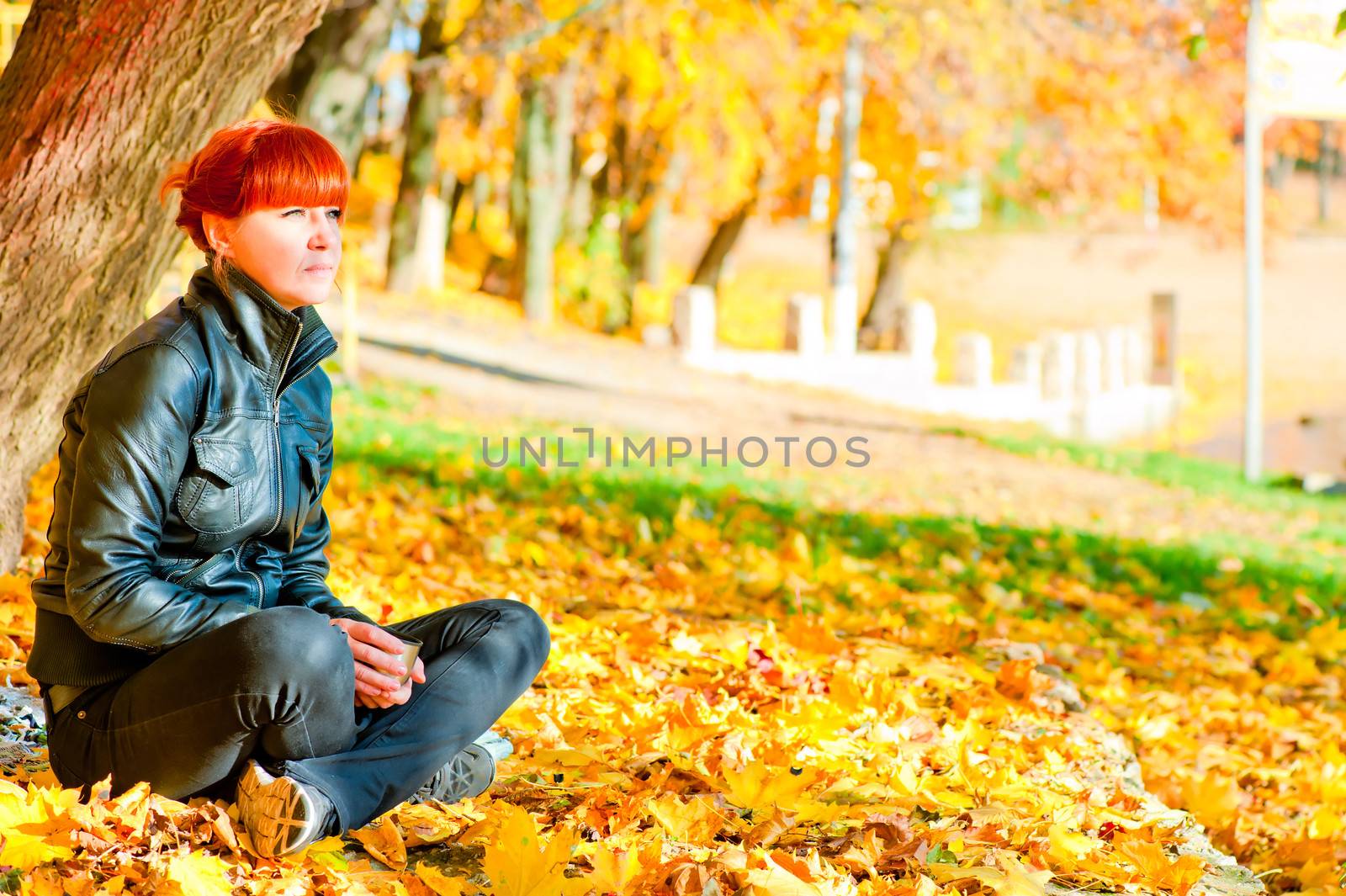 girl with red hair in the park resting in a maple