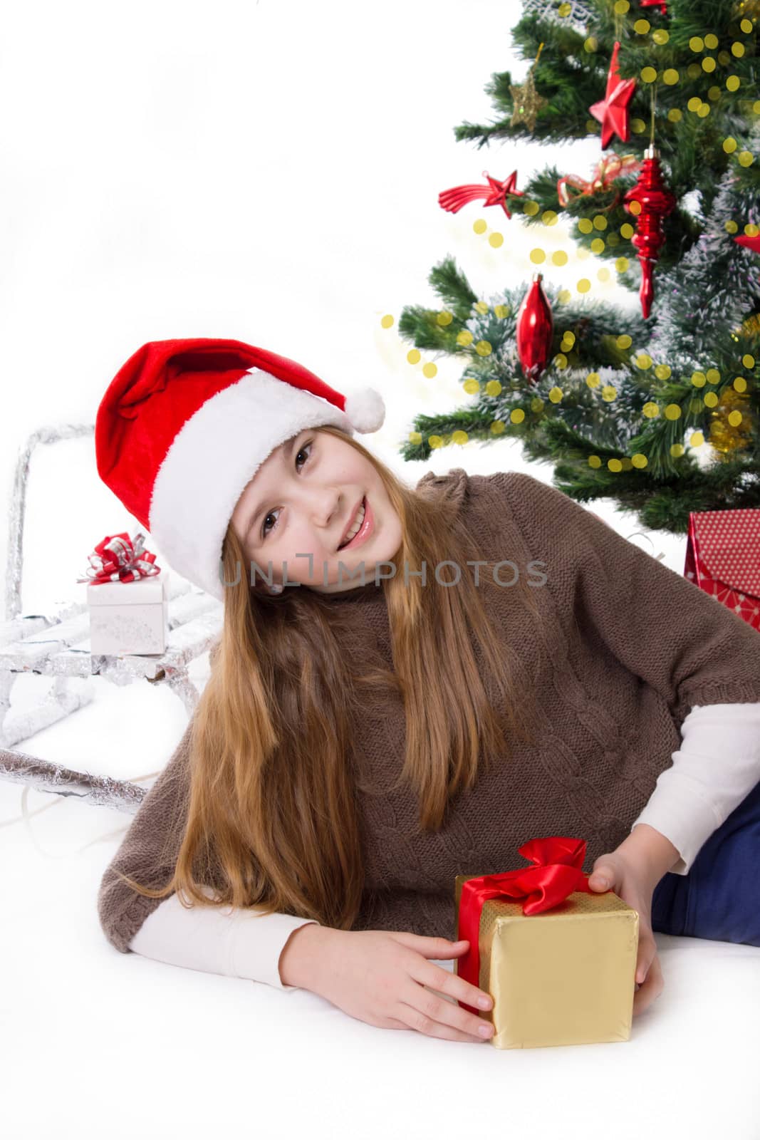 Cute teen girl in Santa hat with gifts under Christmas tree