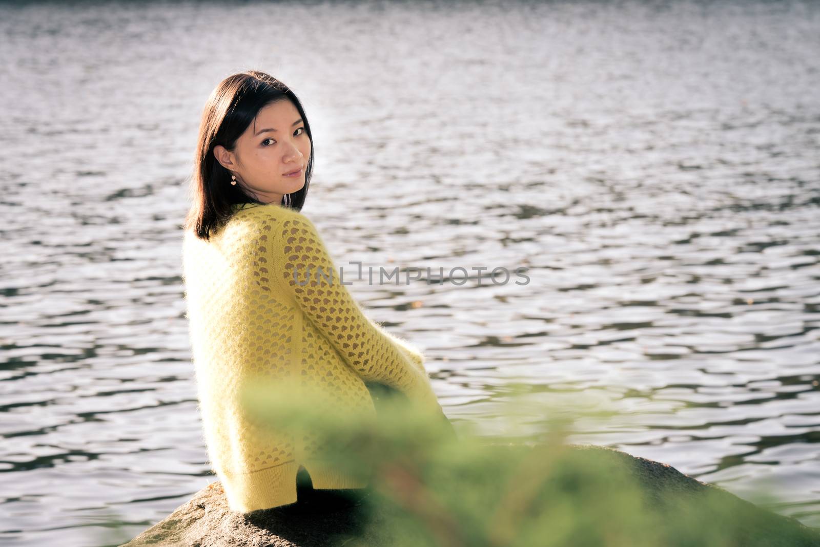 Woman sitting next to a river by IVYPHOTOS