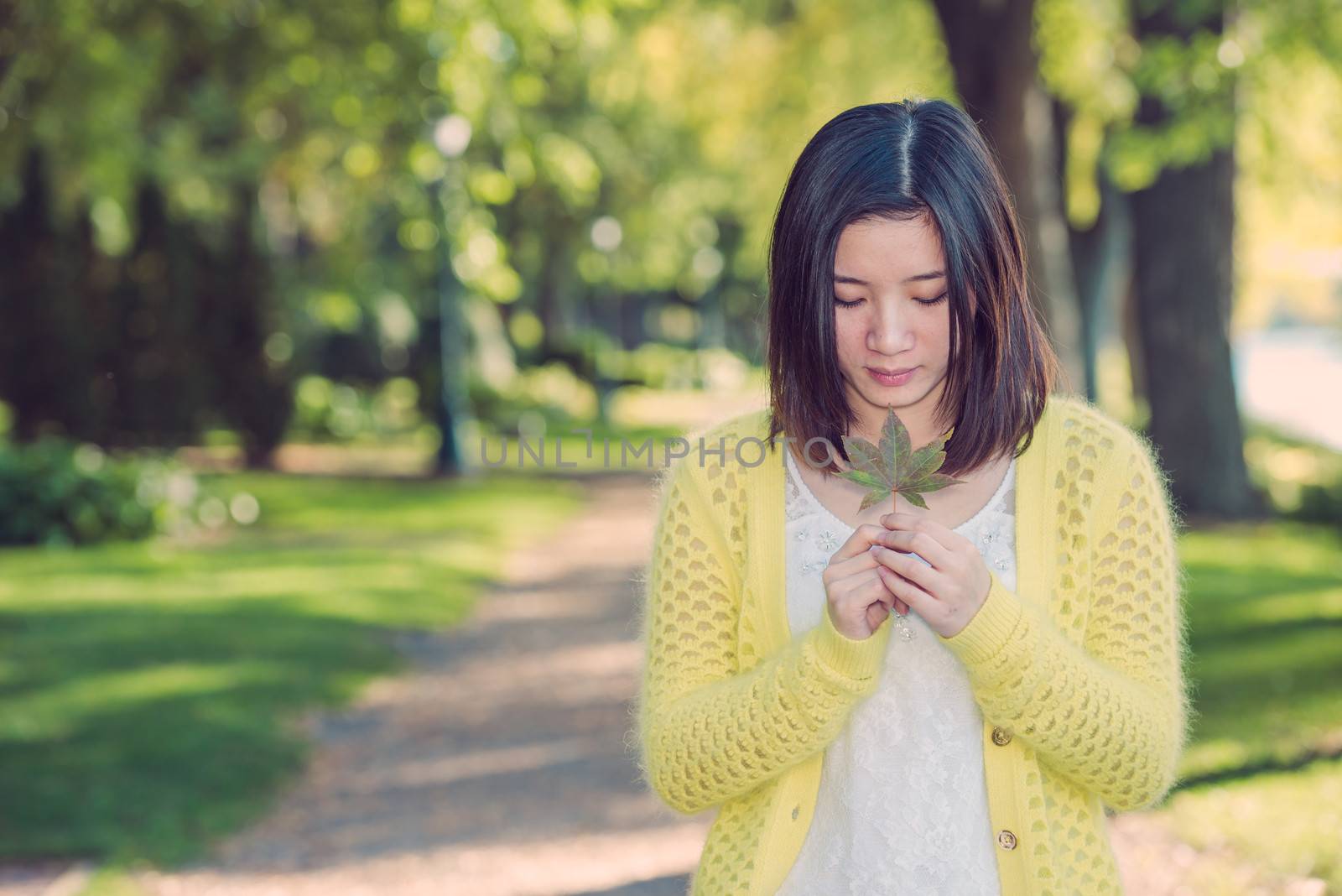 Woman holding a green leaf by IVYPHOTOS