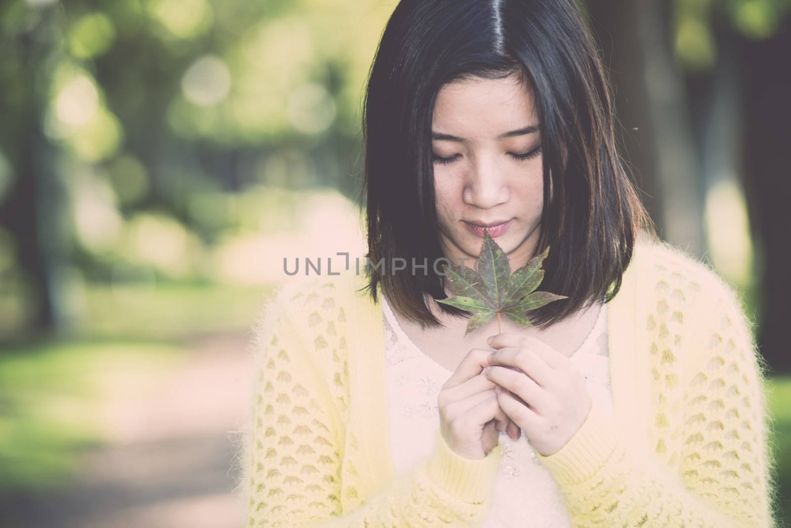 Woman holding a green leaf by IVYPHOTOS