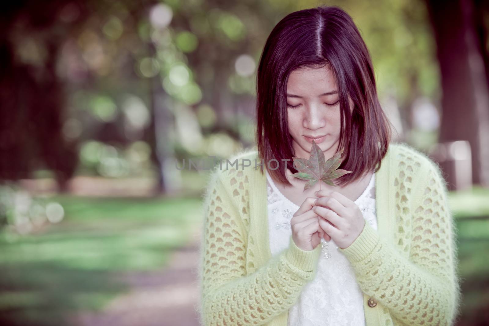 Portrait of young attractive woman holding a leaf close to mouth at an end of a road