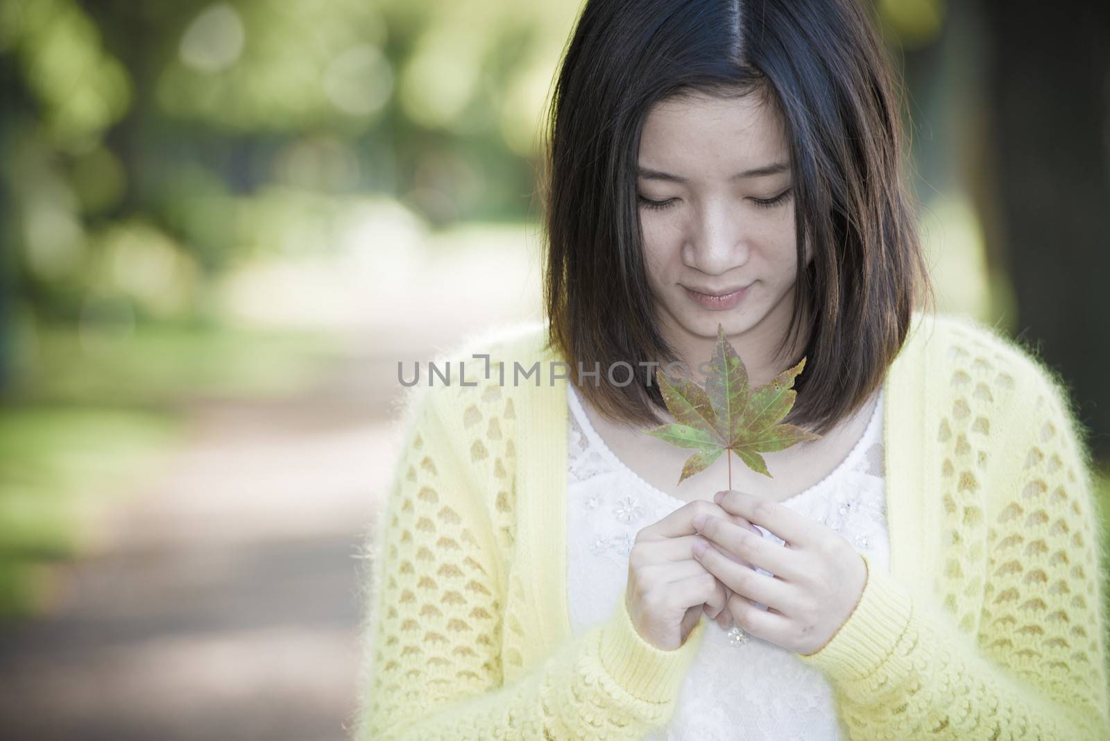 Portrait of young attractive woman holding a leaf close to mouth at an end of a road