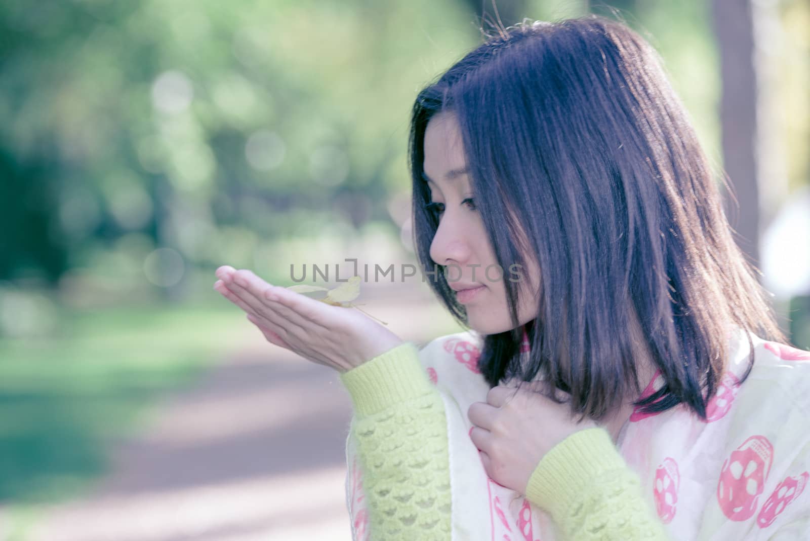 Cute young girl holding a handful of leafs at the end of a park road