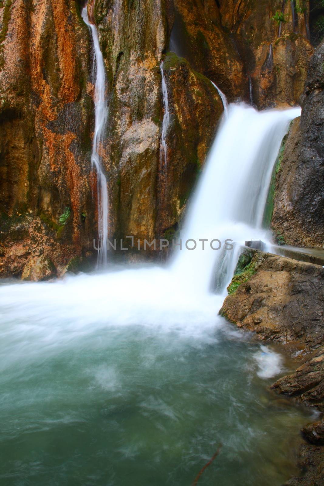 water falling to river between huge rocks 