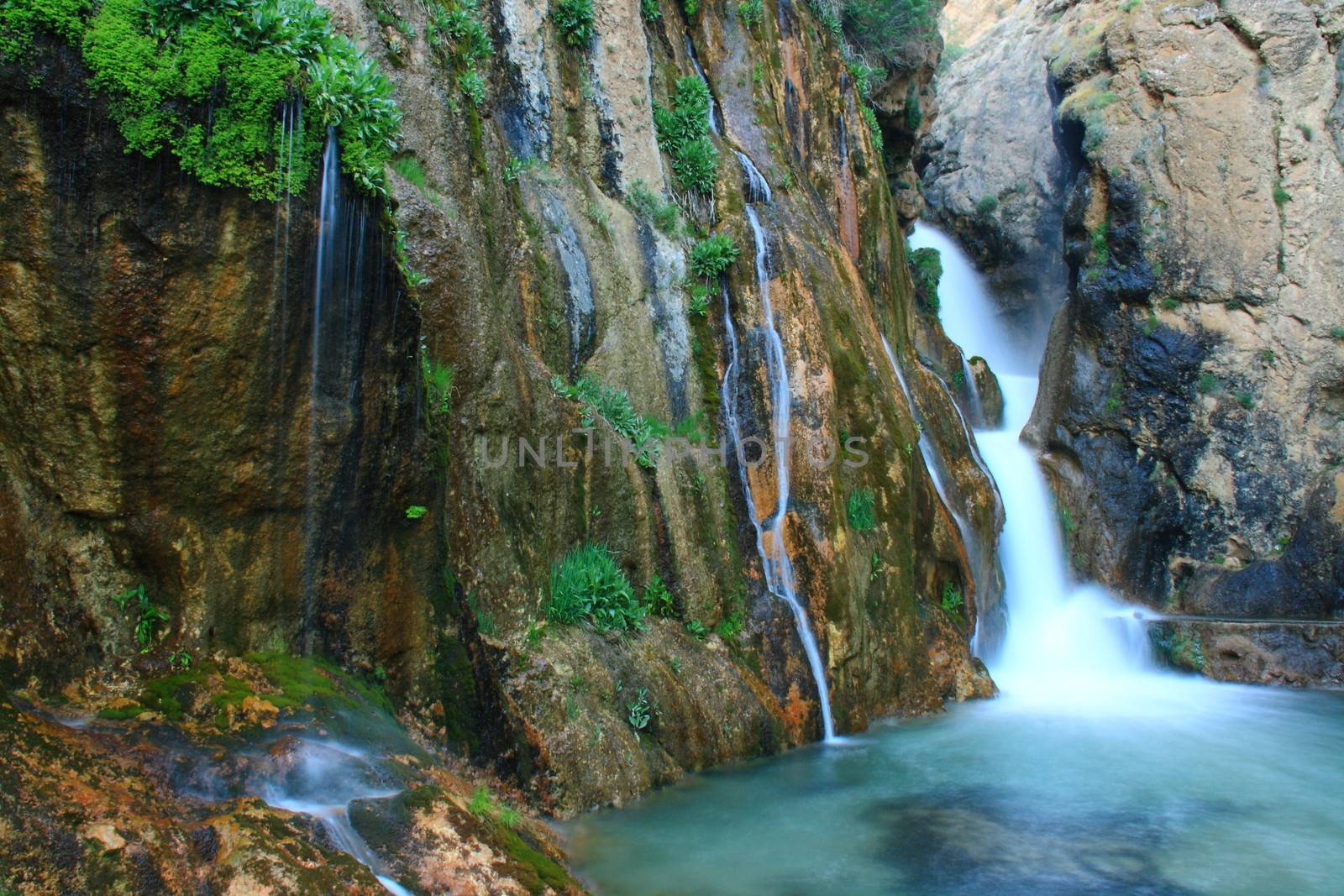 water falling to river between huge rocks 