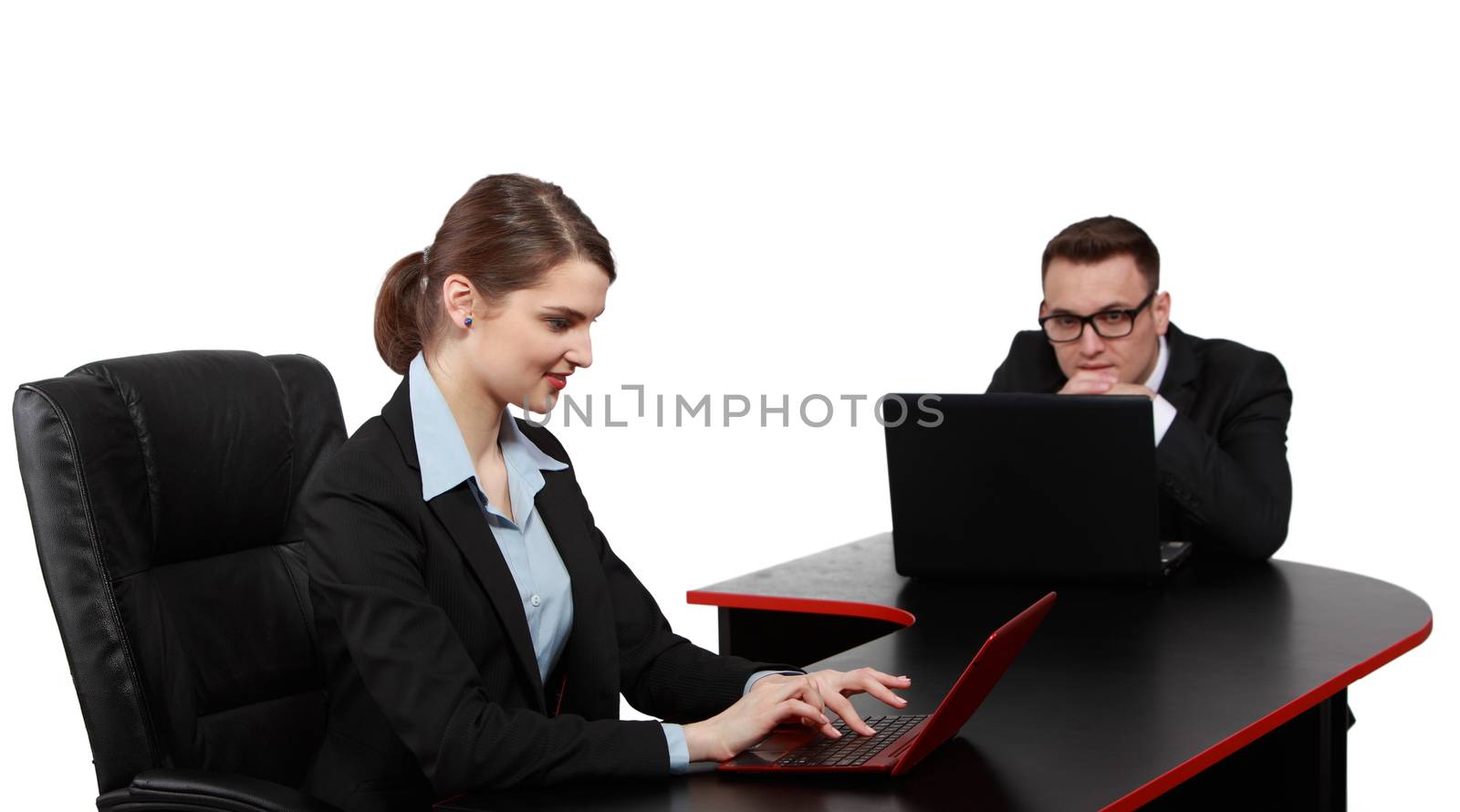 Young business colleagues working on their laptops at the office desk, isolated against a white background.The focus is selective on the man.