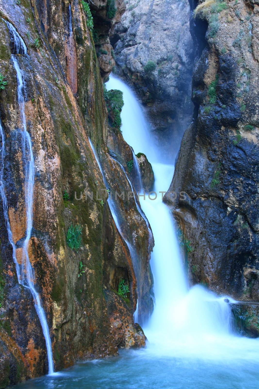 water falling to river between huge rocks 