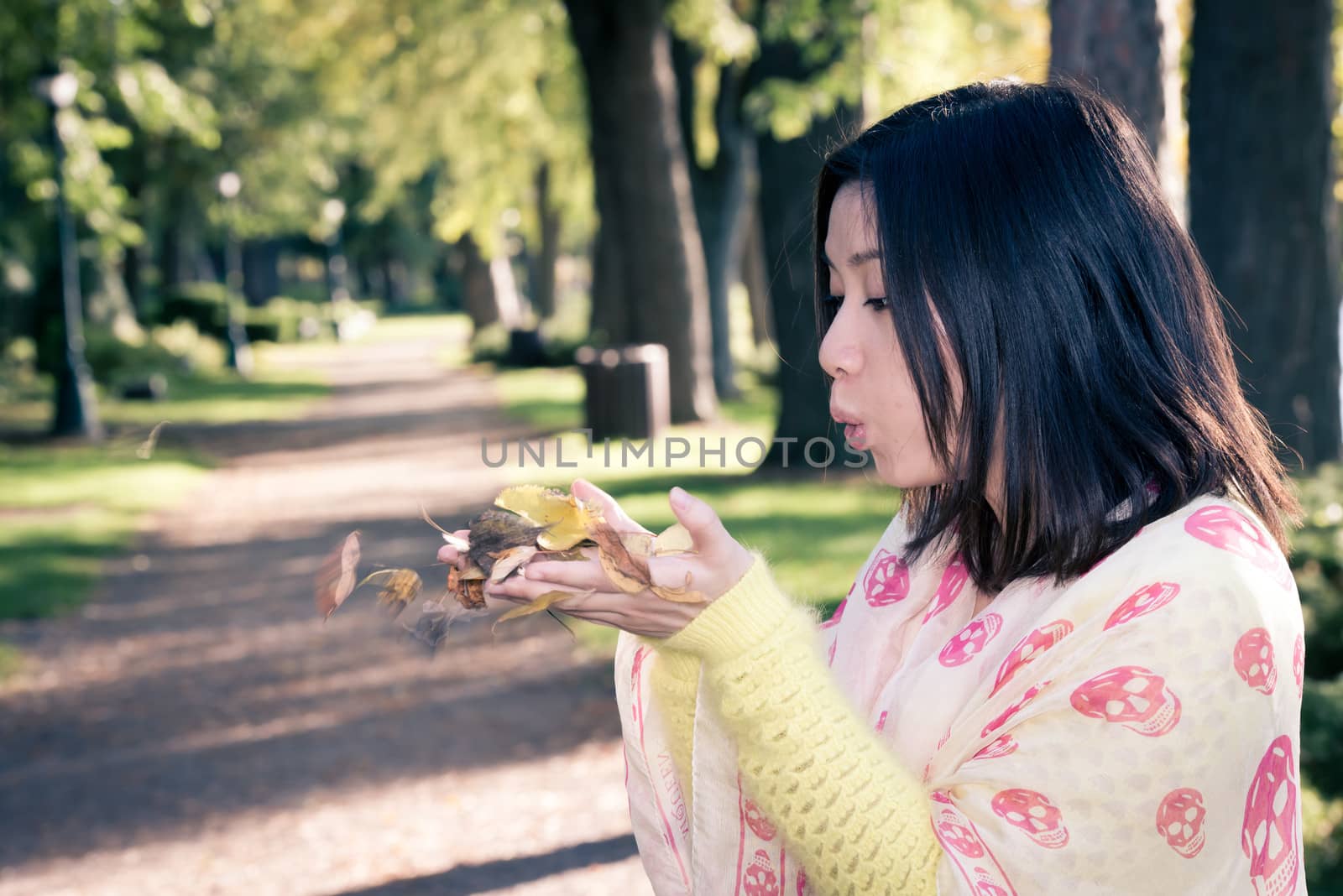 Woman holding leafs in a park by IVYPHOTOS