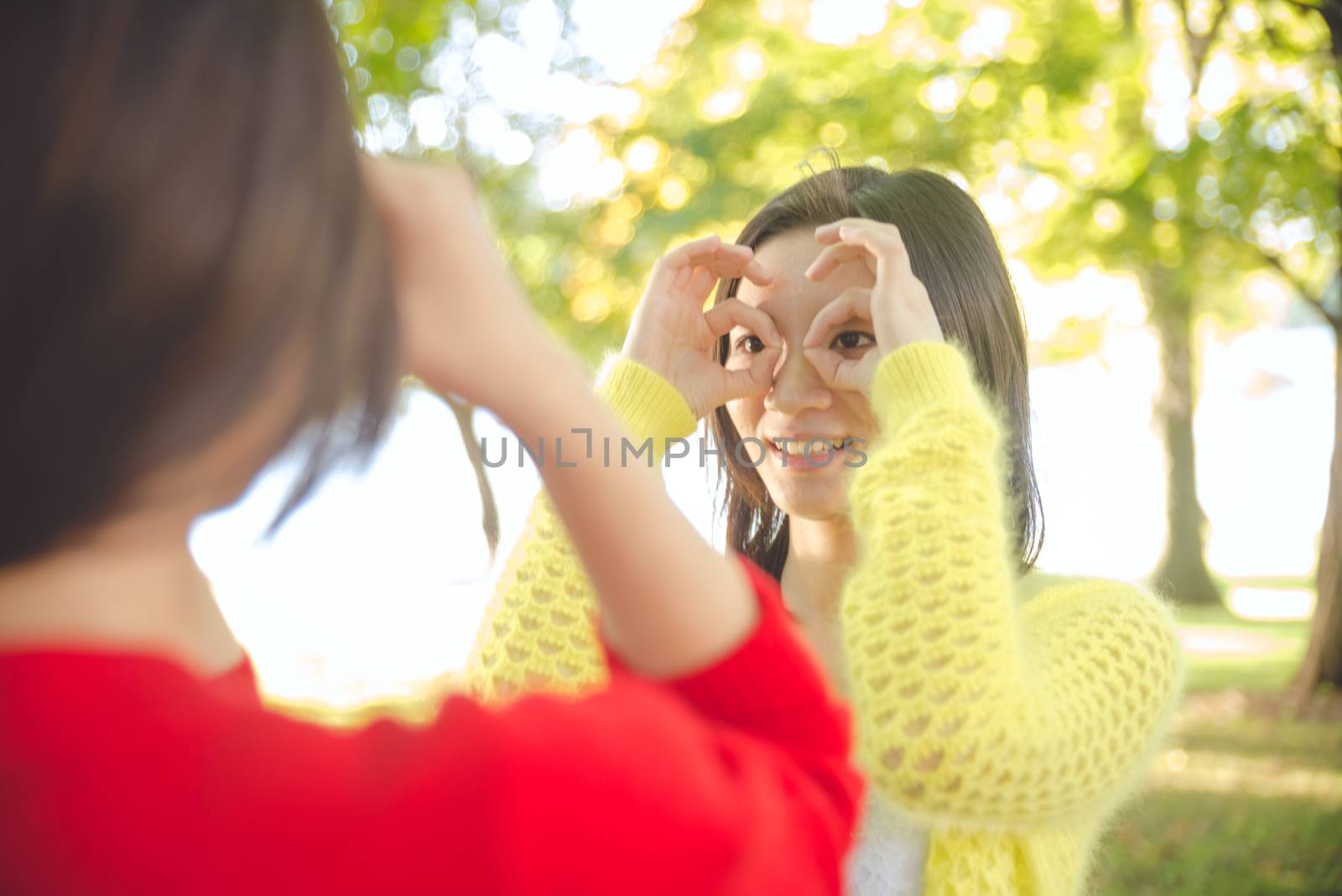 Two young girls posing hand signals to each other in a park showing friendship