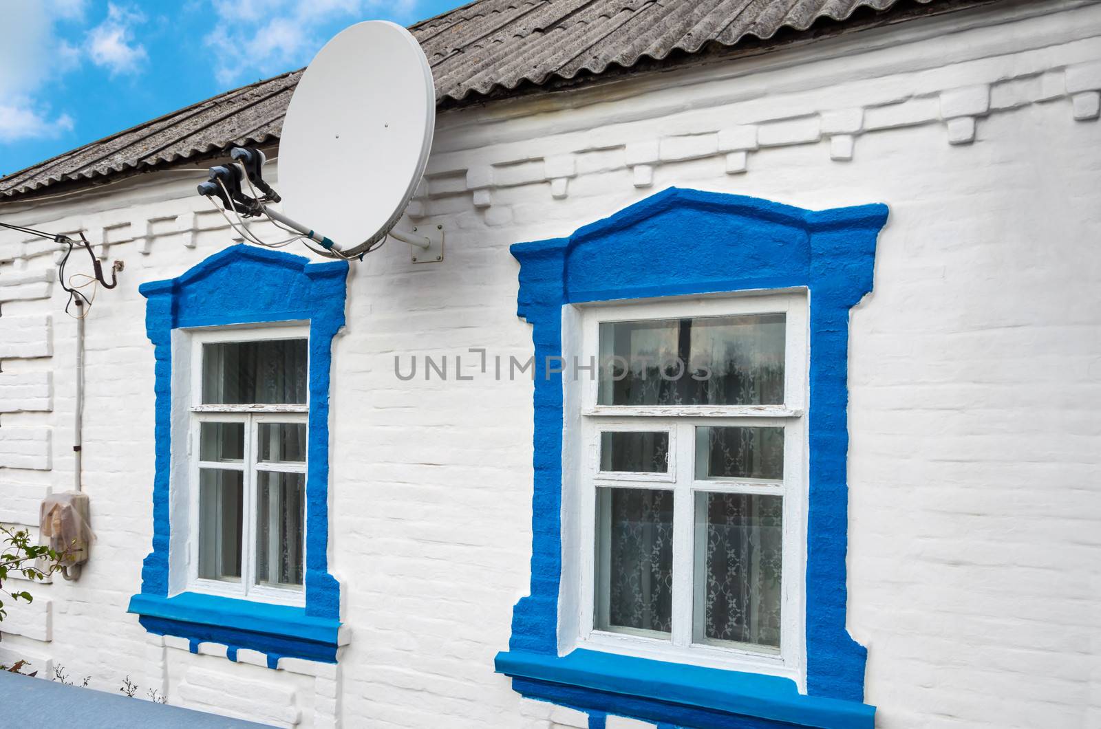 A satellite dish capable of accepting three satellites on the wall of the rural house.