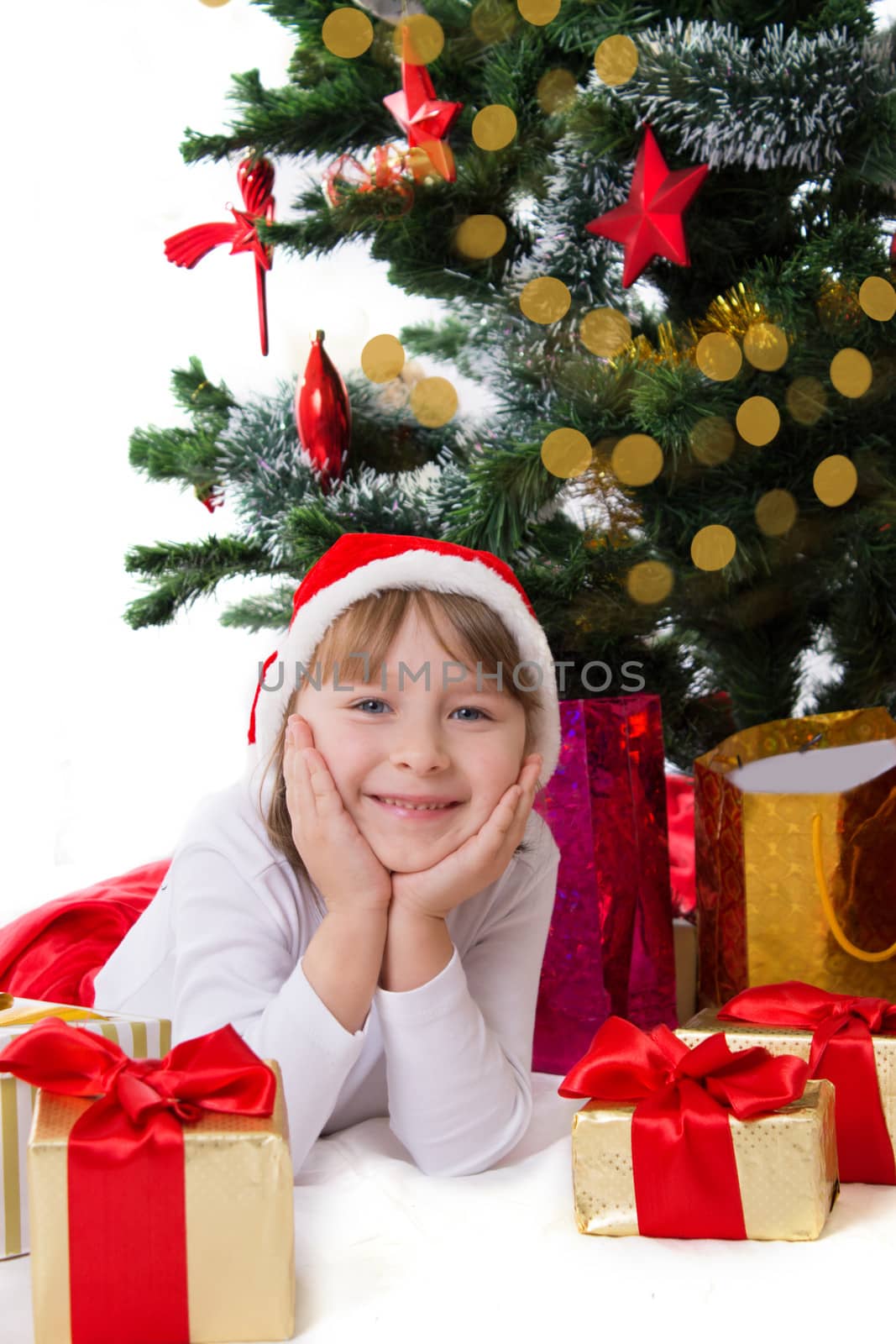 Girl in Santa hat lying under Christmas tree by Angel_a