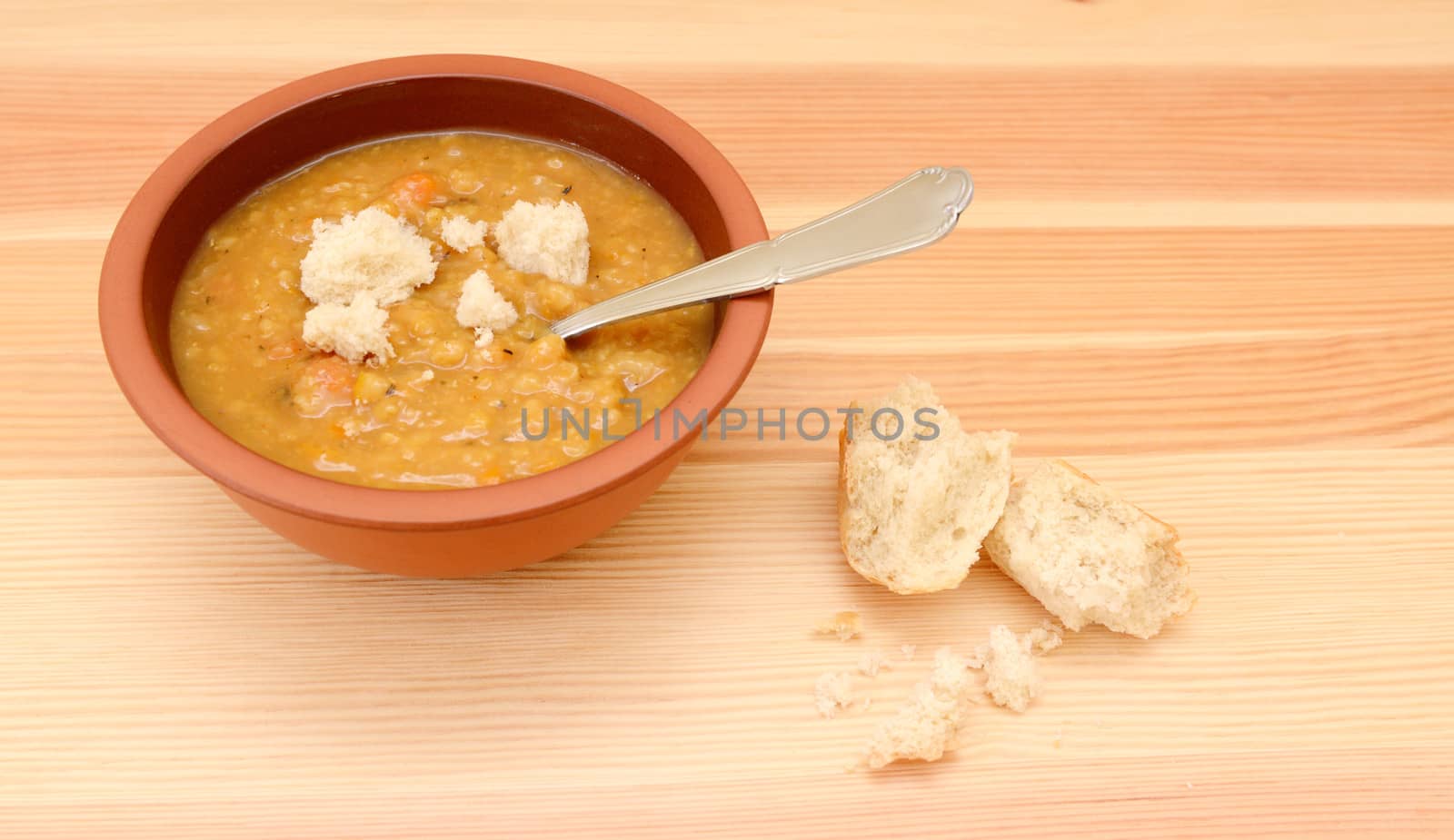 Thick lentil soup dotted with pieces of crusty bread roll