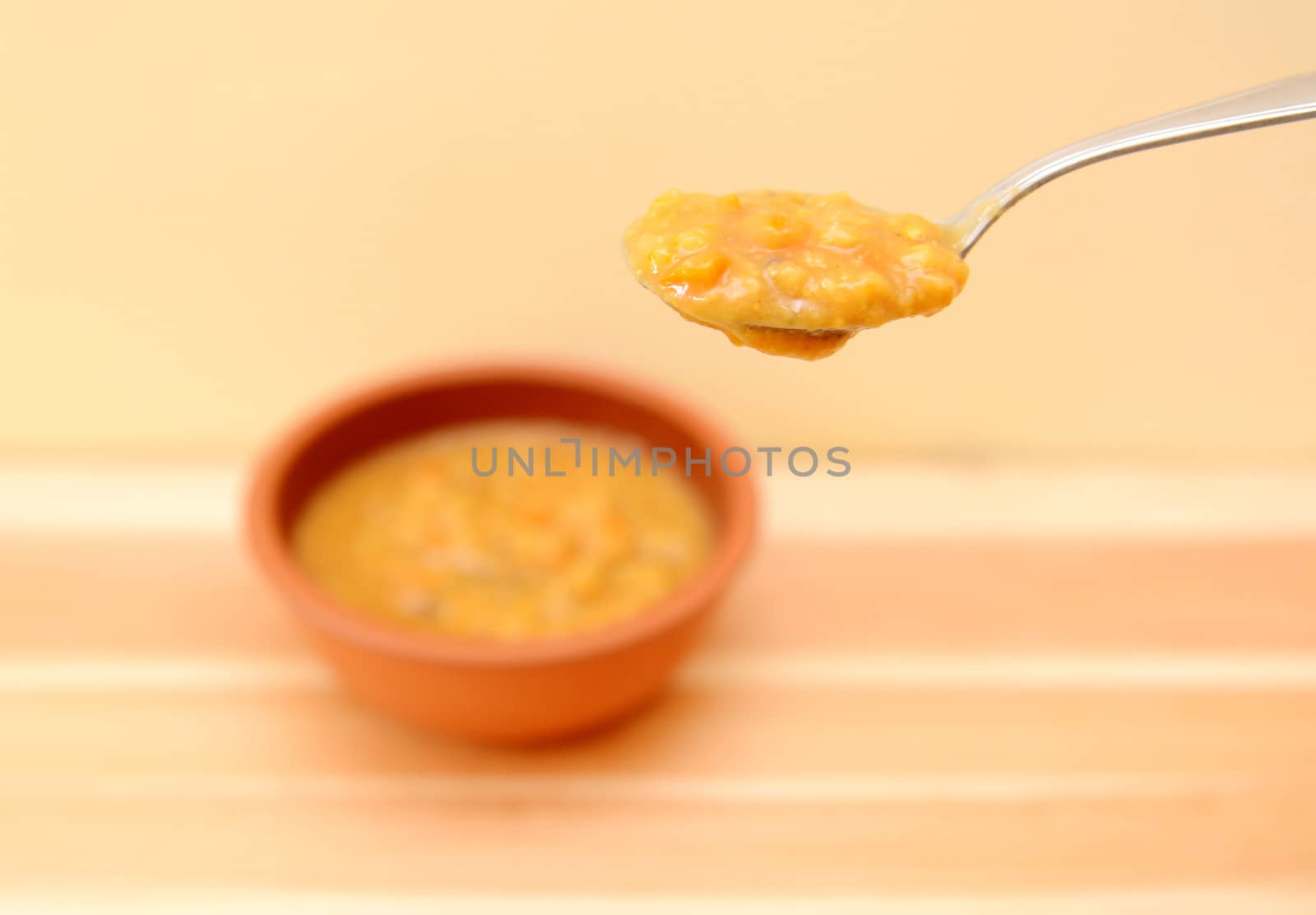 Spoonful of vegetable soup in shallow focus above the bowl with copy space